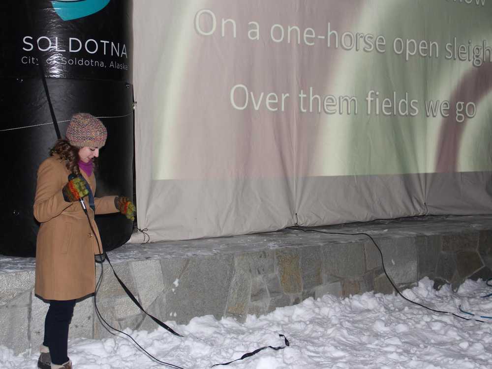 Hannah Taurianen leads the crowd in caroling at Christmas in the Park.