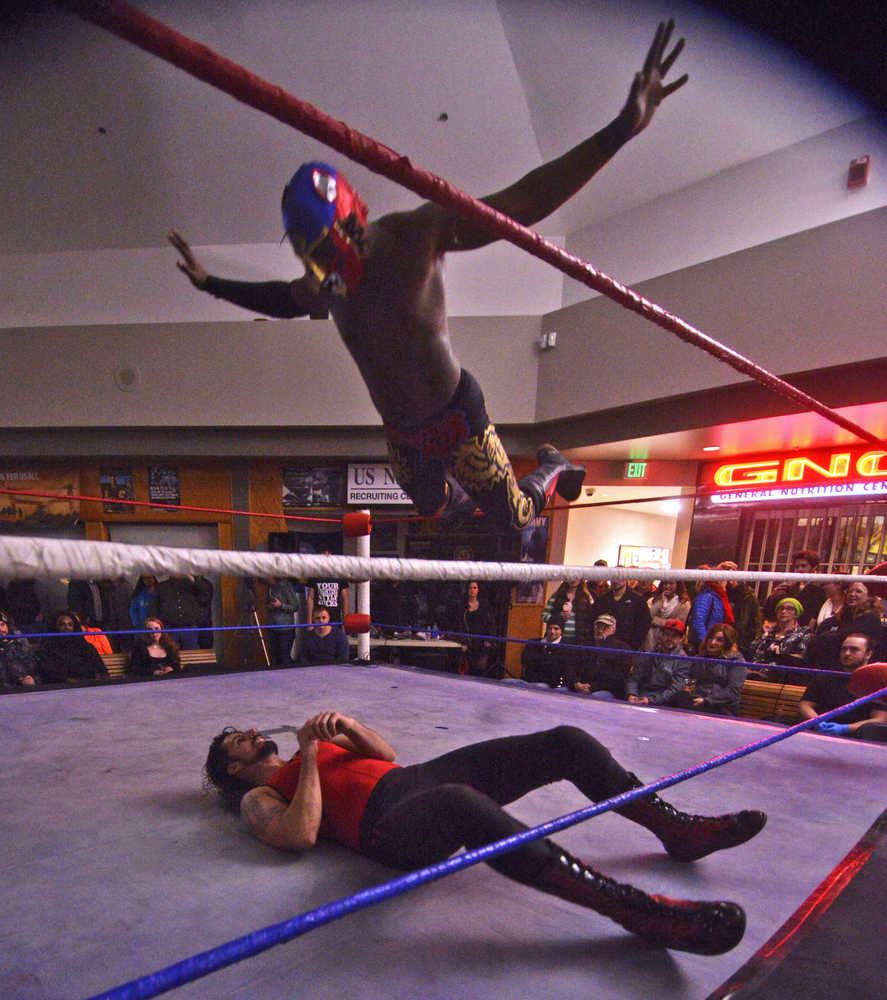 Photo by Ben Boettger/Peninsula Clarion Masked wrestler Phoenix Kid launches off the ropes at his grounded opponent, the Electric Redneck, during a pro-style wrestling match at the Fight Before Christmas martial arts event on Thursday, Dec. 22 in Soldotna's Peninsula Center Mall.