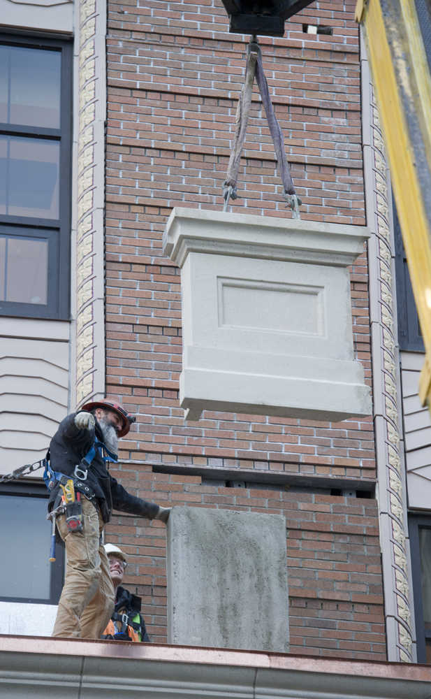 A fixture is lifted into place above the entrance canopy at the Alaska State Capitol building on Thursday.