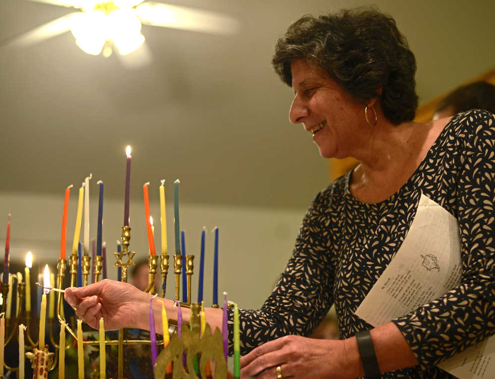 Ben Boettger/Peninsula Clarion Paula Bute of the Kenai peninsula's Briat Elohim Jewish congregation lights the first candles - from which the other candles will be lit - on a collection of menorahs during a Hanukkah celebration on Friday, Dec. 30 near Kenai. In 1983 Bute co-founded Briat Elohim with the late Gary Superman. Although the group usually meets in their own building for worship, they've traditionally celebrated Hanukkah in a member's home, according to secretary Levi Superman, Gary Superman's son.