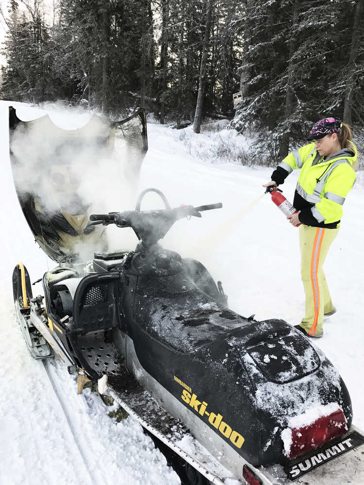 Photo courtesy Laurie Speakman This photos taken Tuesday, Jan. 3, 2017 on Kalifornsky Beach Road between Kenai and Soldotna shows Laurie Speakman, a volunteer driver for the Alaska Moose Federation on the Kenai Peninsula, putting out a snowmobile fire. She used two fire extinguishers to subdue the flames, one from home and one from her truck used to salvage moose, when she noticed a teen in distress on the side of the road.