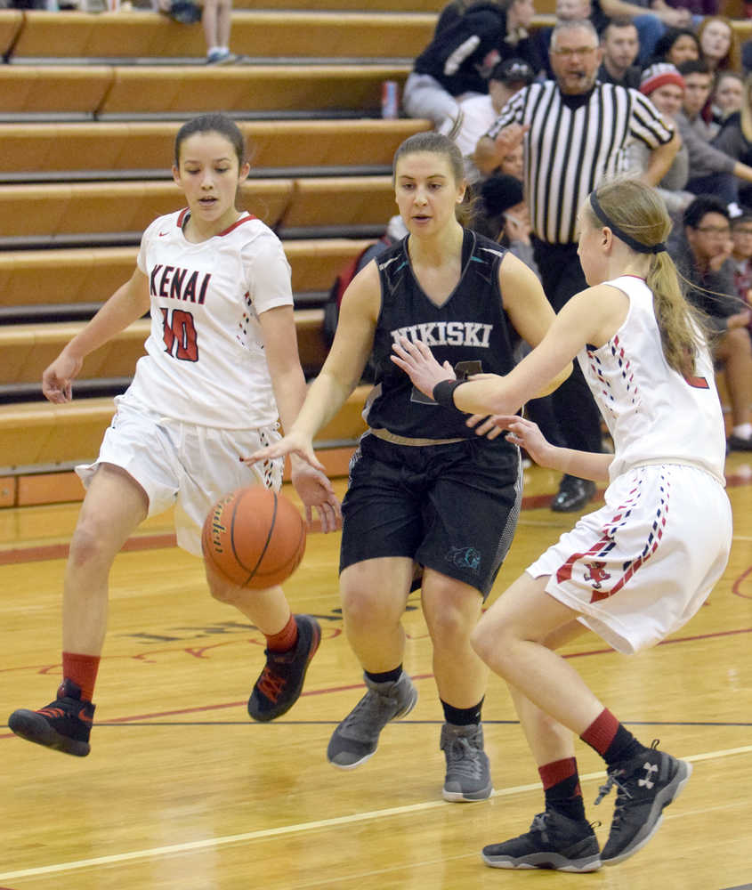 Photo by Jeff Helminiak/Peninsula Clarion Kenai Central's Rebecca Miller taps the ball from Nikiski's Kelsey Clark as Kenai Central's Jaycie Calvert looks on Thursday at Kenai Central High School.