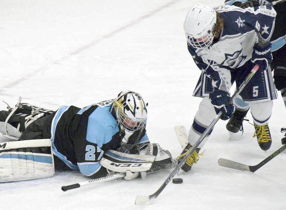 Photo by Joey Klecka/Peninsula Clarion Hutchison goaltender Zach Baxter dives to cover the puck in front of a charging Matthew Daugherty (5) Friday night at the Soldotna Regional Sports Complex.