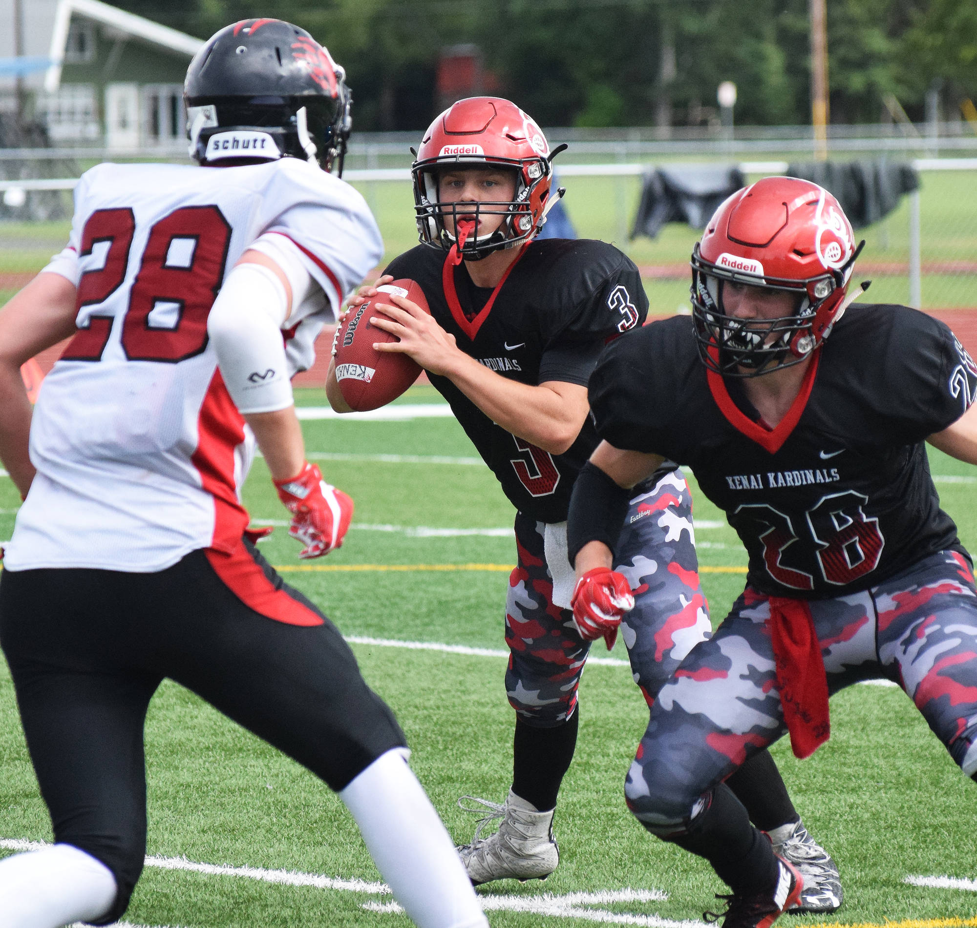 Kenai Central quarterback Connor Felchle looks for an open receiver against Juneau while teammate Rykker Riddall (28) puts up a block Aug. 26, 2017, at Ed Hollier Field in Kenai. (Photo by Joey Klecka/Peninsula Clarion)