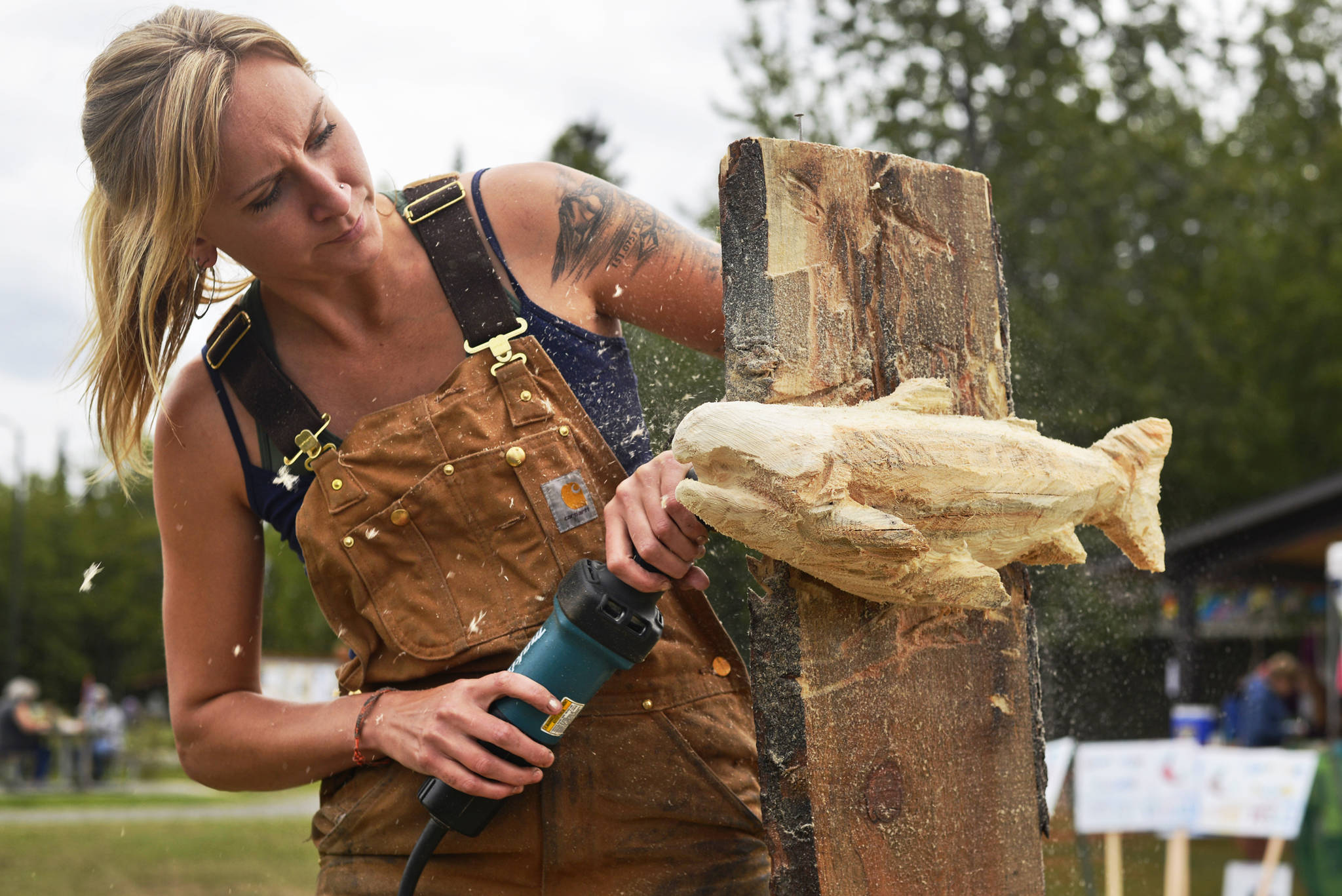 Sculptor Nichole Hoop works on a carving during the Alaska Wild Salmon Day festivities in Soldotna Creek Park on Friday in Soldotna. The event, organized by the conservation nonprofit Cook Inletkeeper, featured salmon-themed art, servings of salmon chowder, readings by fisher-poets, and music by Tyson James and Motown Fever. (Ben Boettger/Peninsula Clarion)