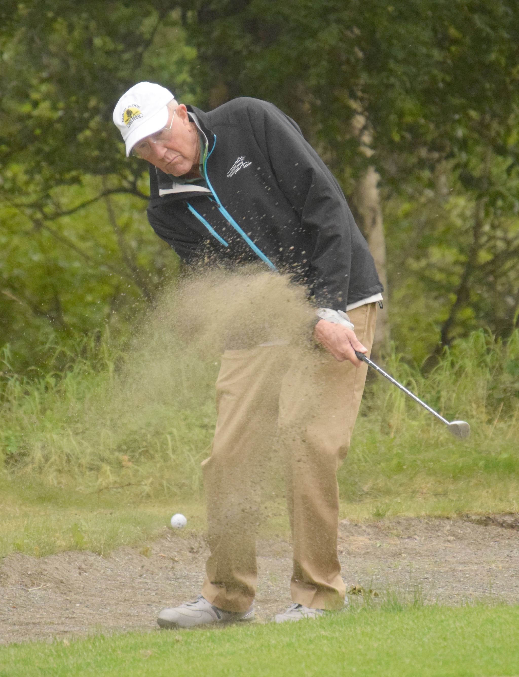 Birch Ridge’s Mike Hollingsworth splashes out of a bunker on the third hole at Kenai Golf Course during the Peninsula Cup on Wednesday, Aug. 18, 2018. (Photo by Jeff Helminiak/Peninsula Clarion)