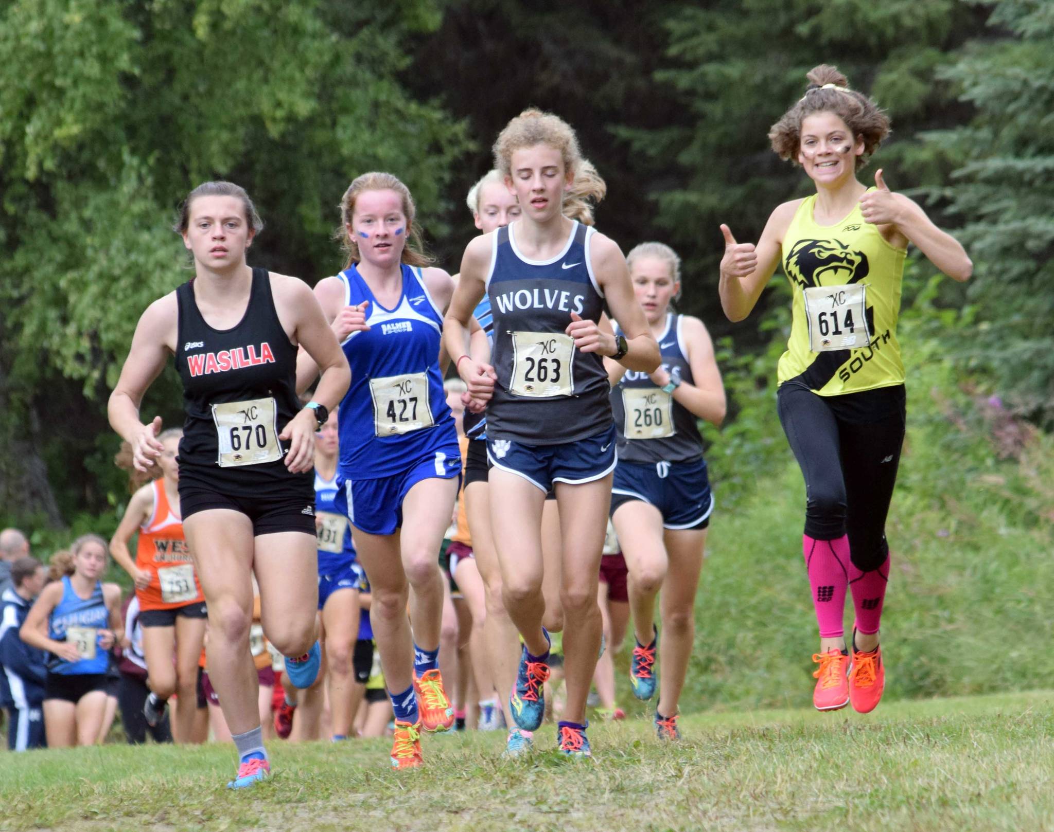 South’s Ava Earl, the eventual winner at far right, gives the thumbs up early in the Tsalteshi Invitational girls varsity race Saturday, Aug. 18, 2018, at Tsalteshi Trails. Running with Earl are Wasilla’s Allison VanPelt, Palmer’s Katey Houser and Eagle River’s Emily Walsh. (Photo by Jeff Helminiak/Peninsula Clarion)