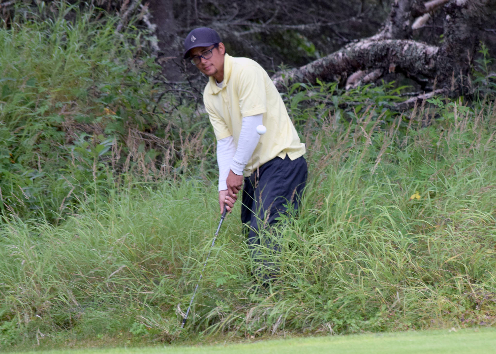 Birch Ridge’s Pedro McCall hacks out of the thick grass behind the 15th green Sunday, Aug. 19, 2018, during the Peninsula Cup at Kenai Golf Course. (Photo by Jeff Helminiak/Peninsula Clarion)