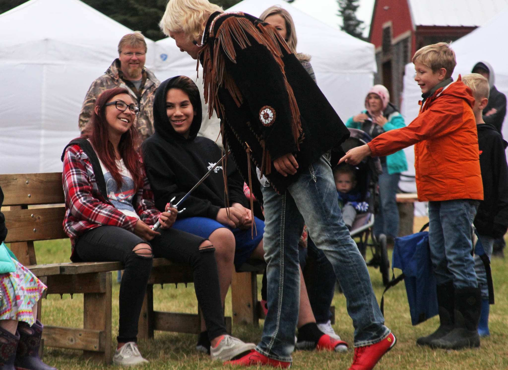 Sword swallower Dan Meyer presents a sword to audience member Cheyenne Juliussen, who pulled the sword out of his throat during Meyer’s last act, on Saturday, August 18, 2018 in Ninilchik, Alaska. (Photo courtesy Ben Boettger)