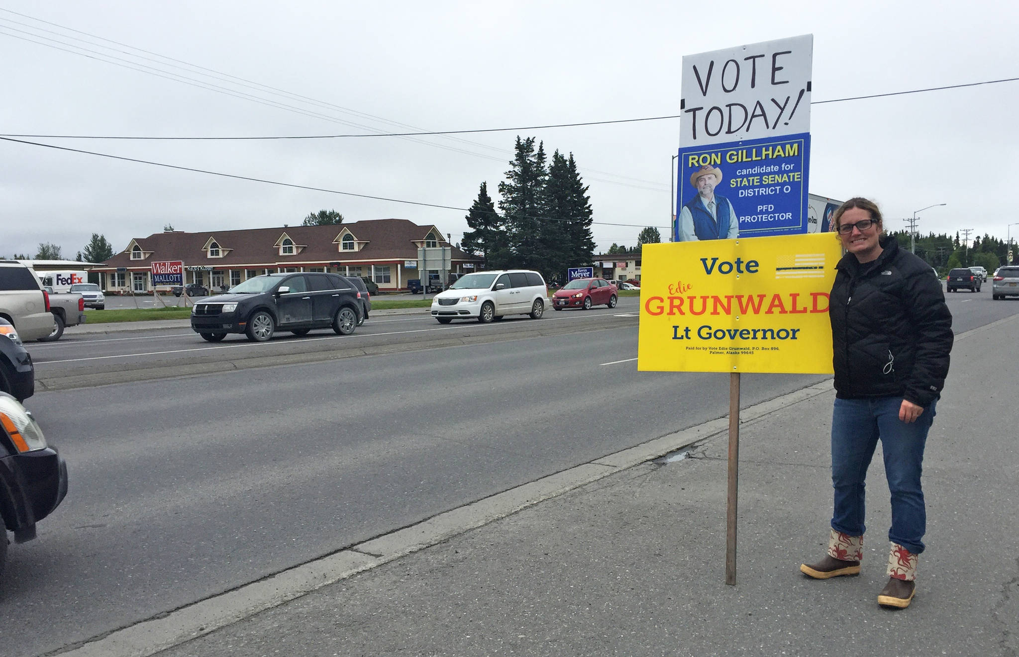 Teea Winger of Kenai waves signs reminding passing drivers to vote in the primary election on the side of the Kenai Spur Highway on Tuesday, Aug. 21, 2018 in Kenai, Alaska. (Photo by Elizabeth Earl/Peninsula Clarion)