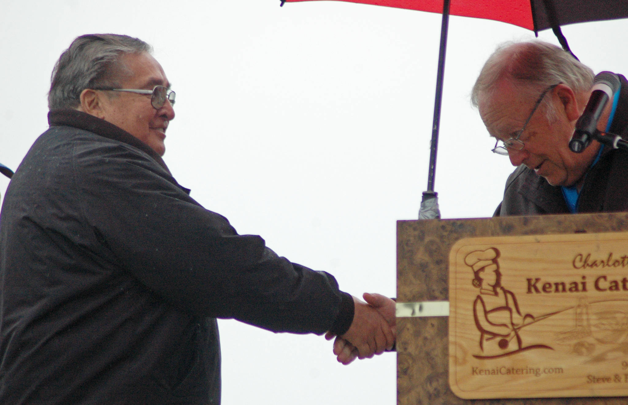 Rep. Mike Chenault, R-Nikiski (right) shakes hands with Kenai commercial fisherman Coby Wilson while presenting him and his wife Connie Wilson with an award at Industry Appreciation Day on Saturday, Aug. 25, 2018 in Kenai, Alaska. (Photo by Elizabeth Earl/Peninsula Clarion)