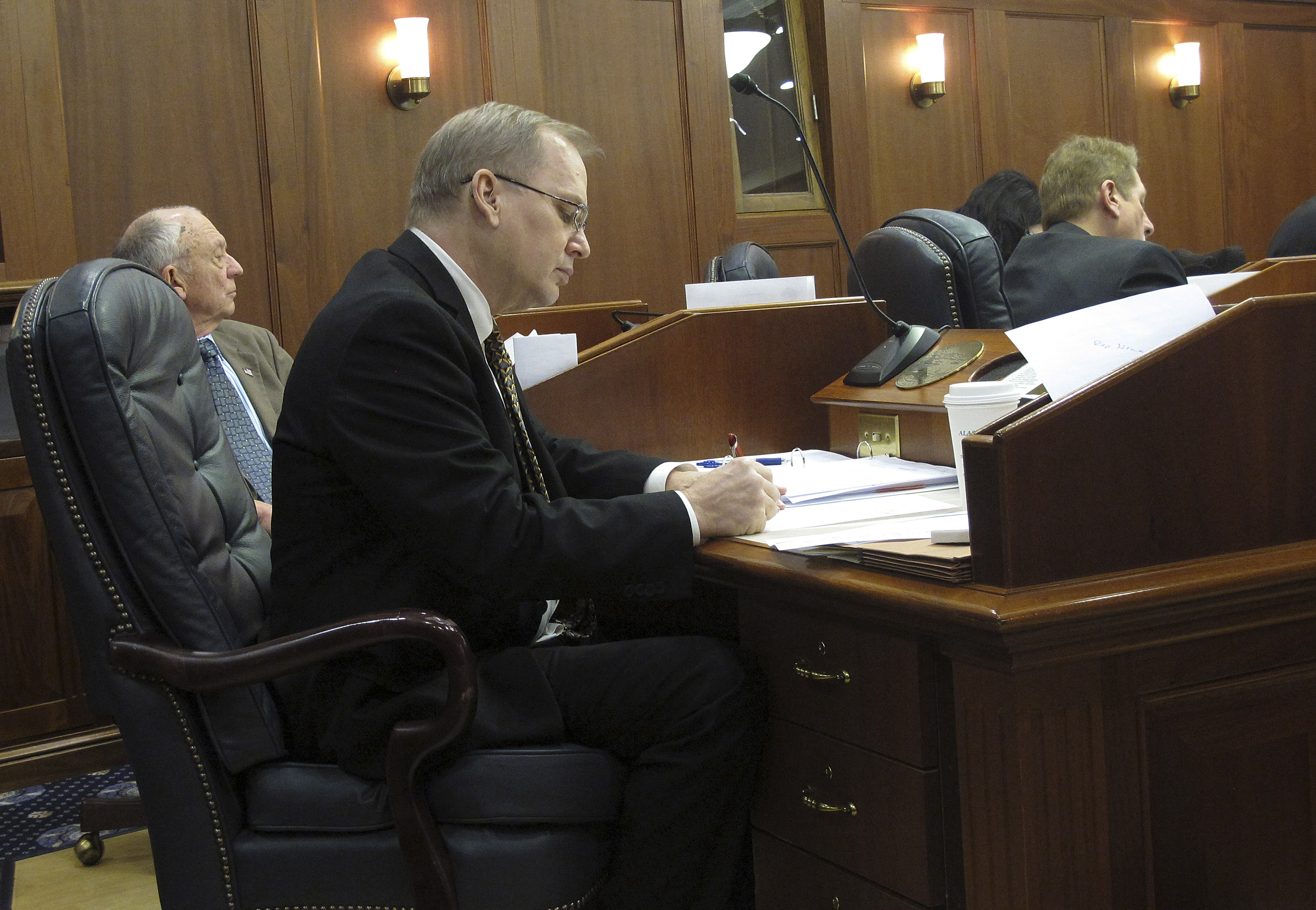 House Finance Committee co-chair Mark Neuman, R-Big Lake, center, writes at his desk on the House floor as debate gets under way on proposed amendments to the state operating budget on Thursday, March 12, 2015, in Juneau, Alaska.