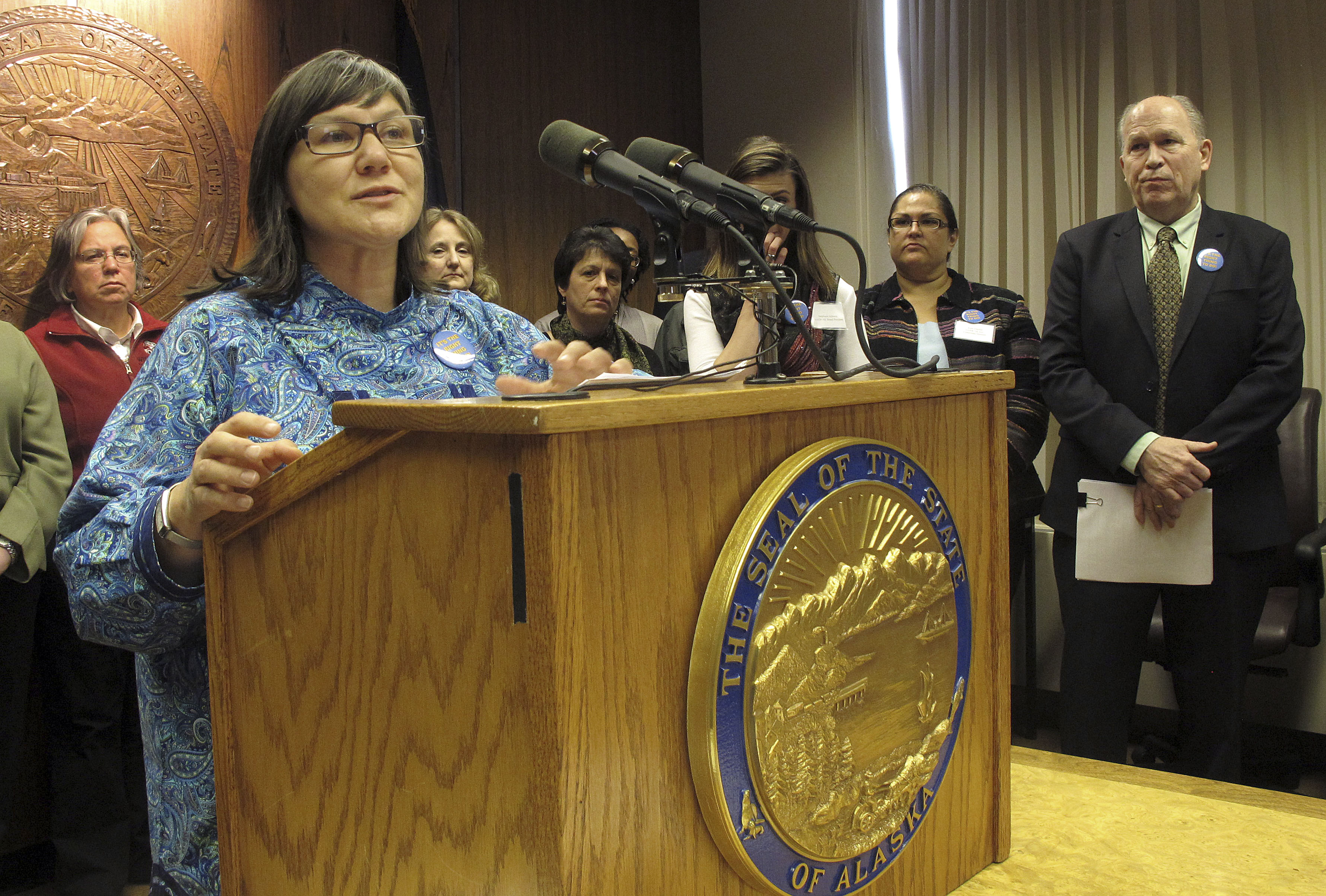 State Health Commissioner Valerie Davidson, left, speaks with reporters during a news conference as Gov. Bill Walker, far right, watches on Tuesday, March 17, 2015, in Juneau, Alaska. Walker announced plans to introduce legislation to reform and expand the Medicaid system in Alaska.