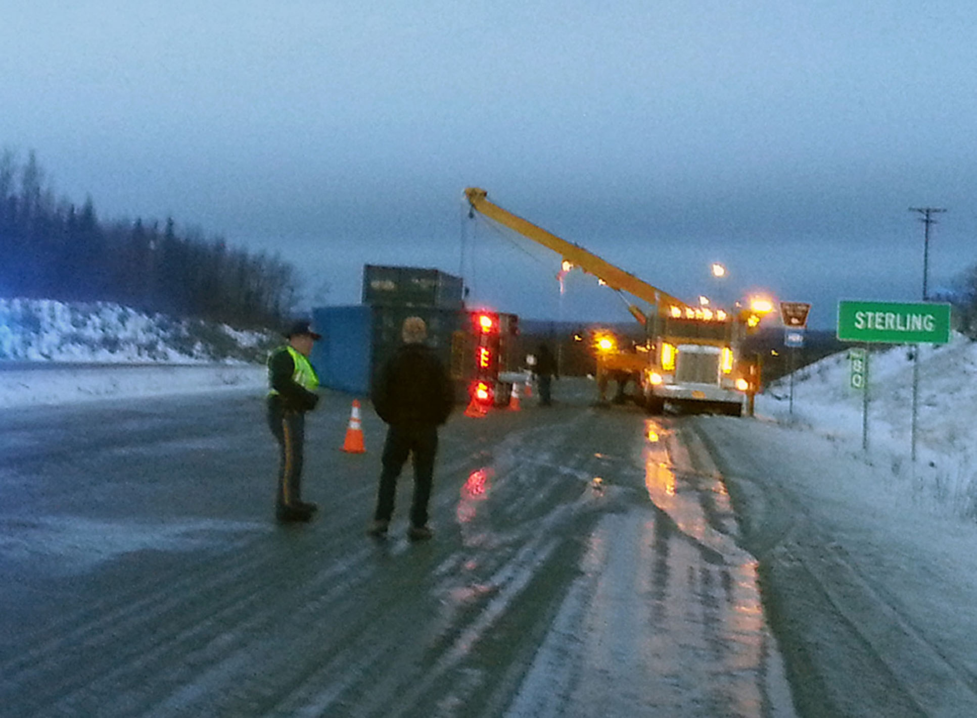 Alaska State Trooper John King talks to a motorist Monday, Dec. 15, 2015 after a truck trailer lost control on the ice and overturned at Mile 80 of the Sterling Highway. The accident occured at 4:45 a.m. Traffic was backed up half a mile for nearly an hour while a tow truck with a crane attempted to put the trailer upright. The scene was cleared by 11 a.m. The National Weather Service calls for freezing rain for Tuesday morning.