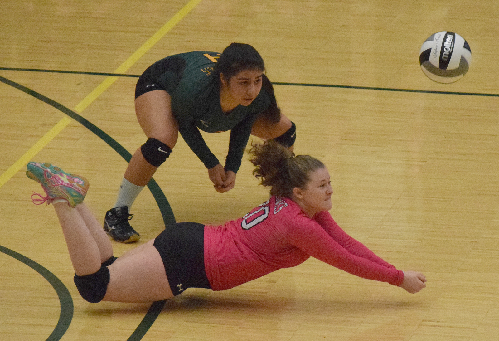 Seward libero Kimmie Hubbard (in pink) digs for a ball with teammate Tia Miranda, Friday against Monroe Catholic in the Class 3A state volleyball tournament held at the Alaska Airlines Arena in Anchorage.
