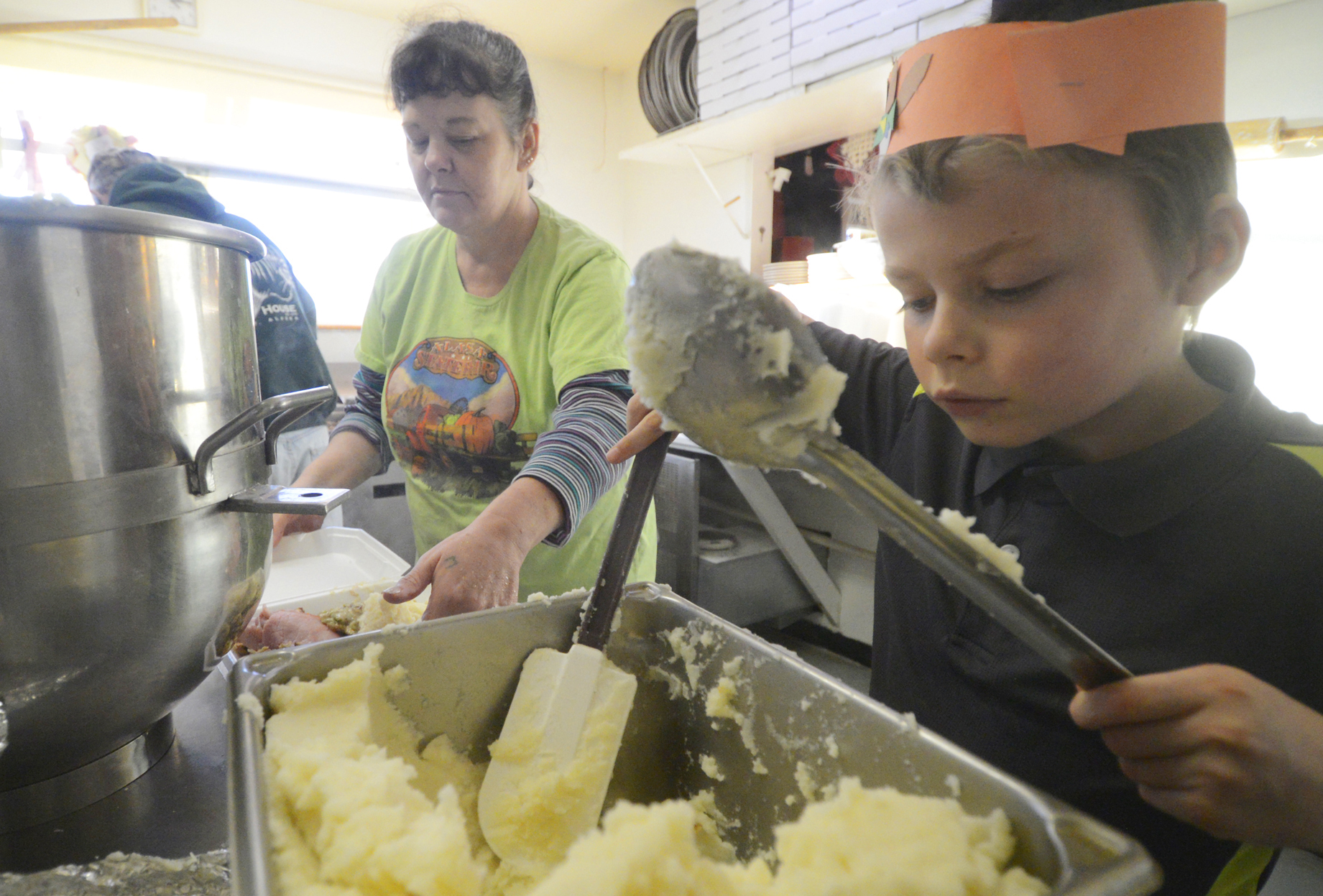 Dalton Goodnight serves up mashed potatoes at Charlie's Pizza in Nikiski for free meals the restaurant delivers to residents on Thanksgiving day Thursday, Nov. 27, 2014, in Nikiski Alaska. Owner Steve Chamberlain said Felix Martinez, owner of M & M Supermarket in Nikiski, donates a dozen turkeys every year for the holiday.