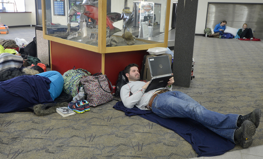 Andrew Spicher, of New York, messes around on his computer as he and several Alyeska-bound friends wait to leave the Kenai Municipal Airport Saturday March 15, 2014 in Kenai, Alaska.