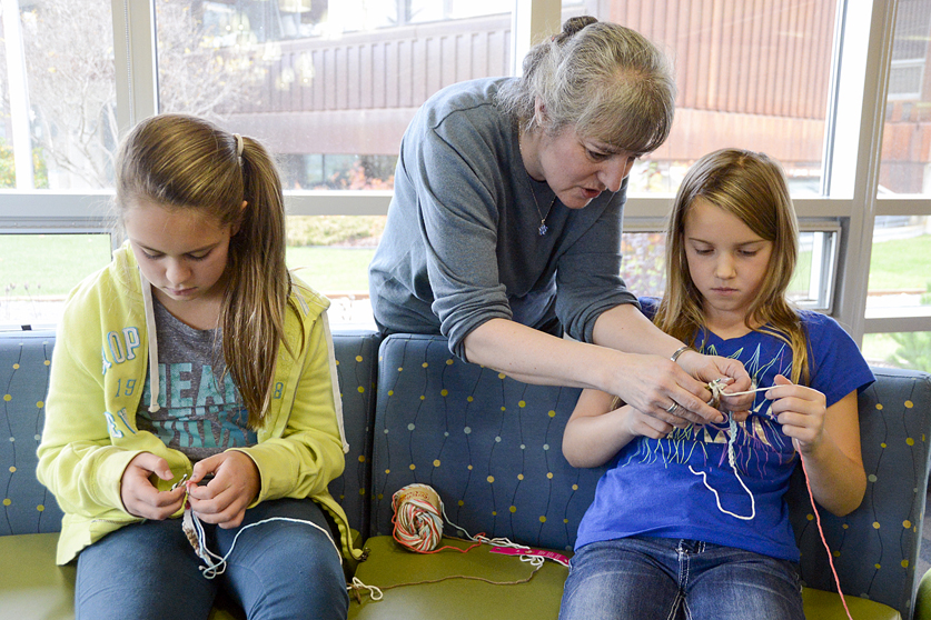 Library Aide Lilly Knackstedt assists Ciara Neely, left, and Ella Yrague, right, during a beginners crochet class on Sunday, Oct. 11, 2015 at the Kenai Public Library in Kenai.