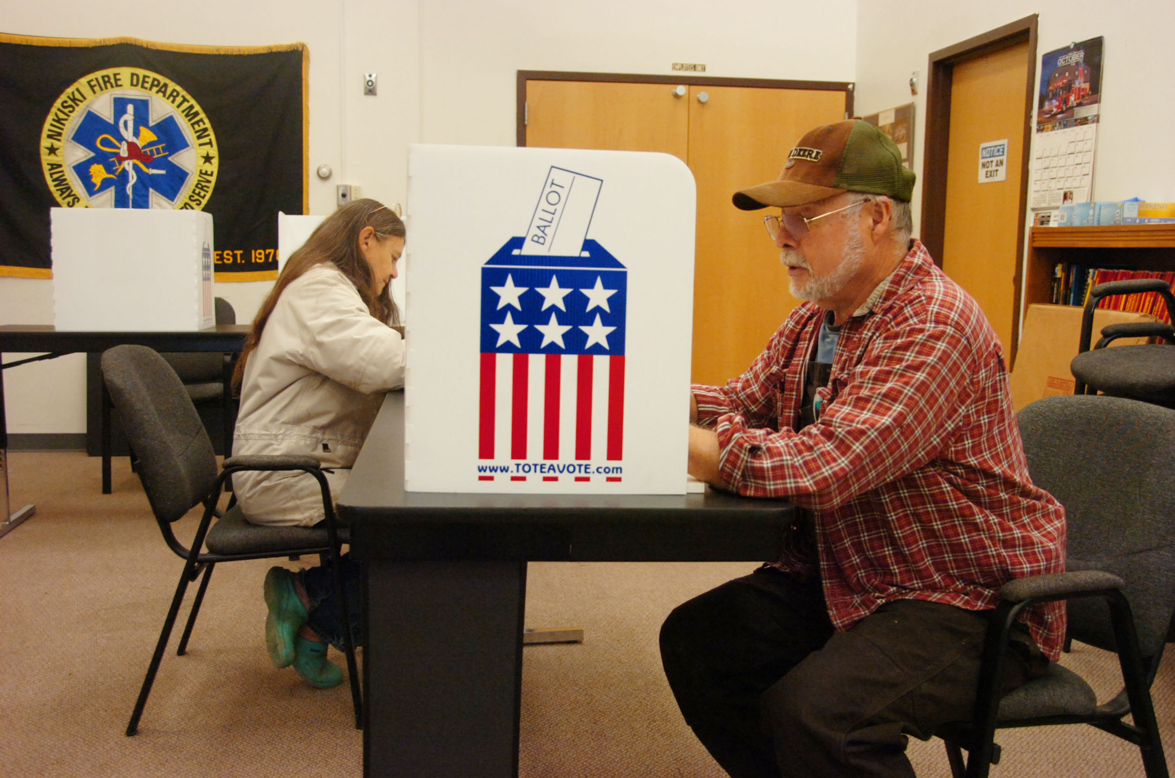 Nikiski residents Lynda Moore, left, and Ewin Frothingham, right, cast their votes during the regular election on Tuesday, Oct. 6, 2015 at the Nikiski Fire Department Station 1 poll location in Nikiski, Alaska.