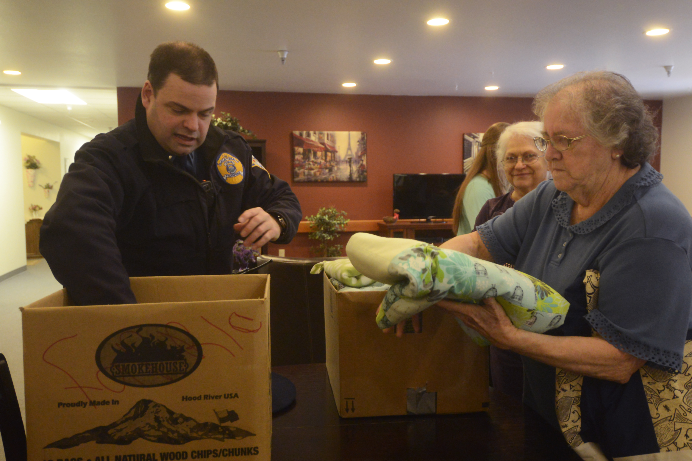 Lt. Dane Gilmore of the Alaska State Troopers accepts 26 hand-made quilts from a group of crafters on Thursday, March 11, 2016 at Northwood Apartments in Soldotna, Alaska. Through several cooperating agencies, the blankets are given out to children in need or involved in investigations.