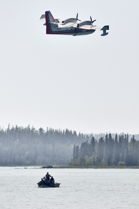 In this June 16, 2015 file photo a group of fishermen watch as a water bomber takes water from Skilak Lake to fight the Card Street wildfire on  near Sterling, Alaska.