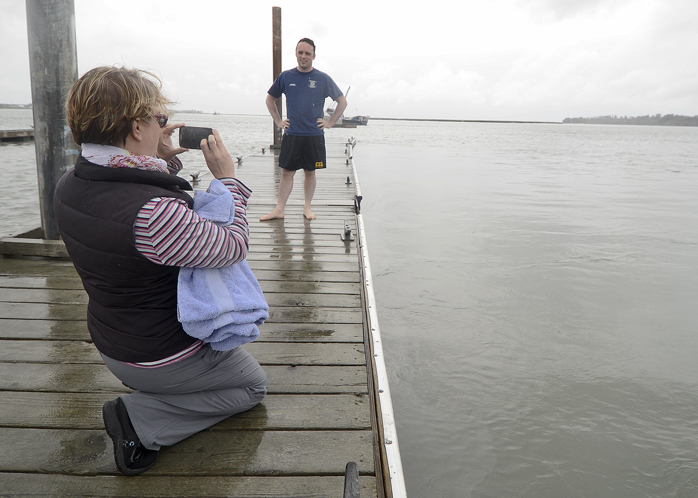 Jessica Bookey films her firefighter husband Terry Bookey as he prepares to jump off of the Kenai City Dock as part of a Cold Water Challenge for charity in Kenai, Alaska.