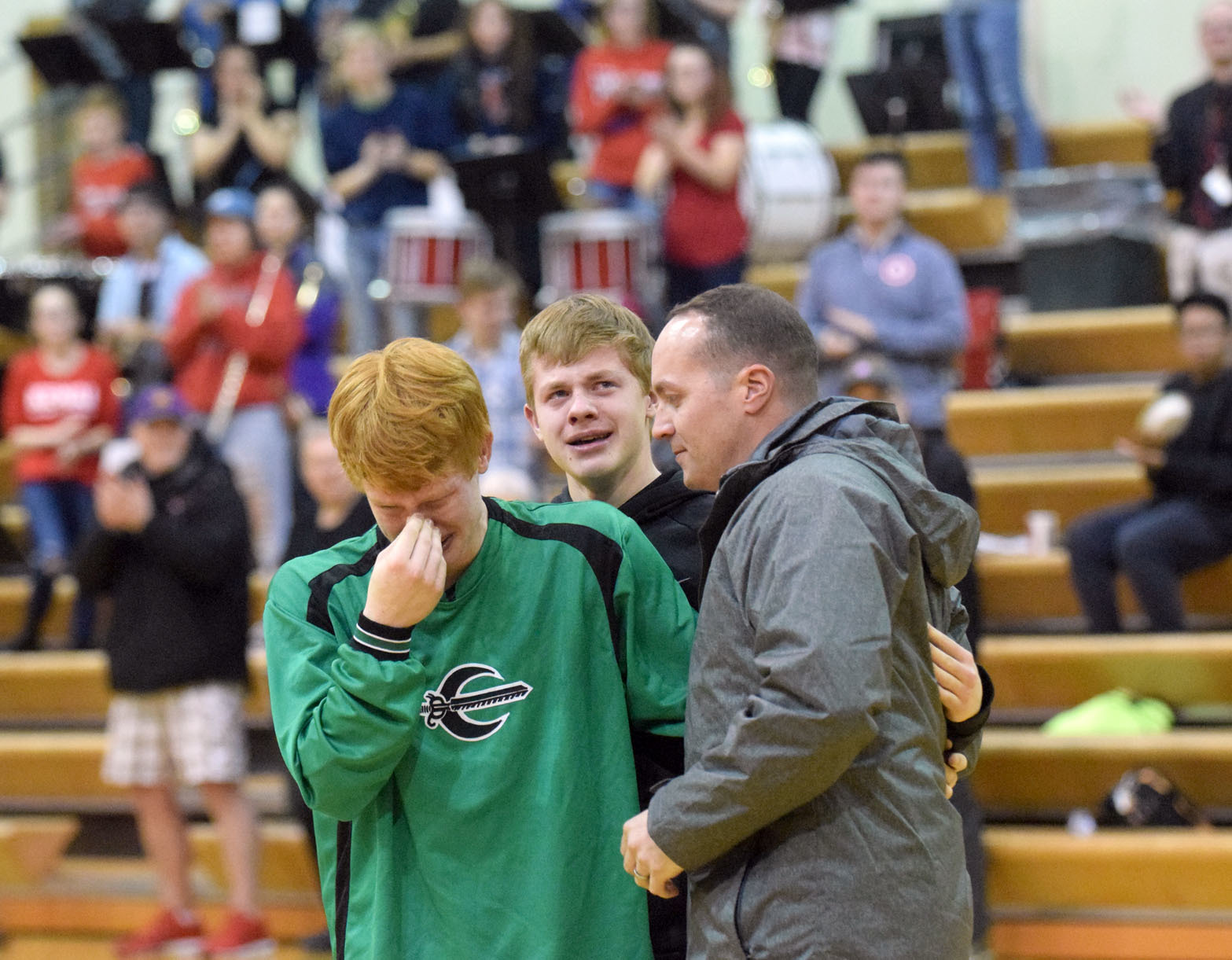 Maj. Josh Pead (right) embraces his sons Nick and Cameron in an emotional hug before Thursday night's varsity boys basketball game at Kenai Central High School. Pead, a physican in the Army, made a surprise appearance after returning from a six-month military deployment in the Middle East. (Photo by Jeff Helminiak/Peninsula Clarion)