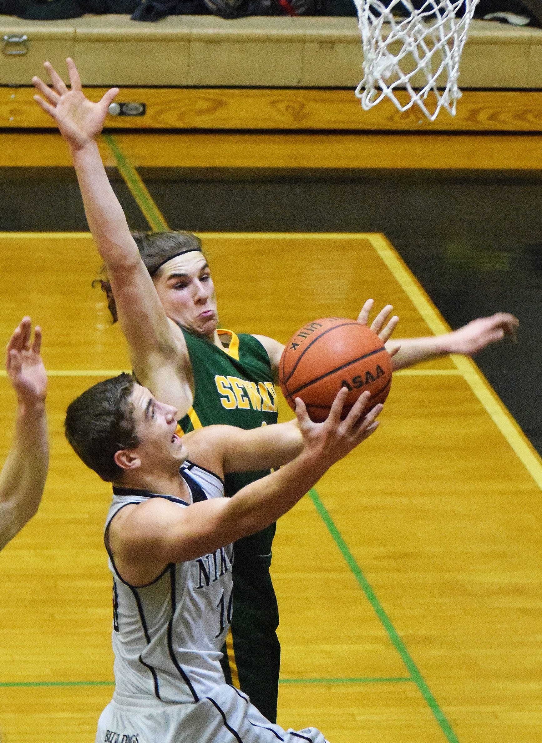 Nikiski’s Ian Johnson drives to the rim against Seward defender Nik Pahno in a Friday night matchup at Nikiski High School. (Photo by Joey Klecka/Peninsula Clarion)