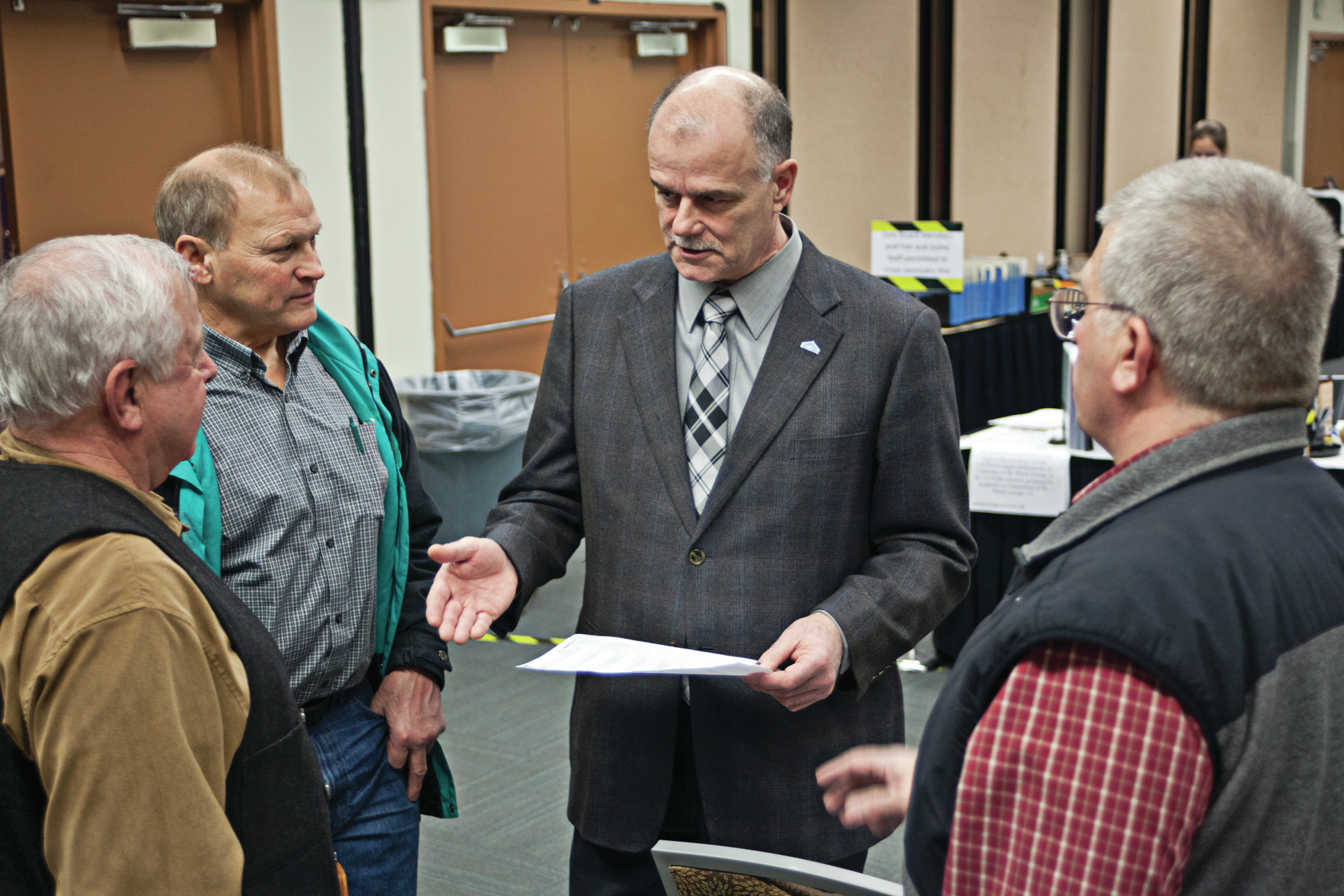 At left, Roland Maw and Dave Martin, both from the United Cook Inlet Drift Association, talk with Board of Fisheries member John Jensen, center, and Bruce Gabrys, a commercial drift fisherman, during the 2014 Upper Cook Inlet Board of Fisheries meeting in Anchorage. On Jan. 18, the state secured an indictment against Maw for 12 felonies and five misdemeanors alleging he illegally obtained Permanent Fund Dividends from 2009-14. (Photo/File/Peninsula Clarion)