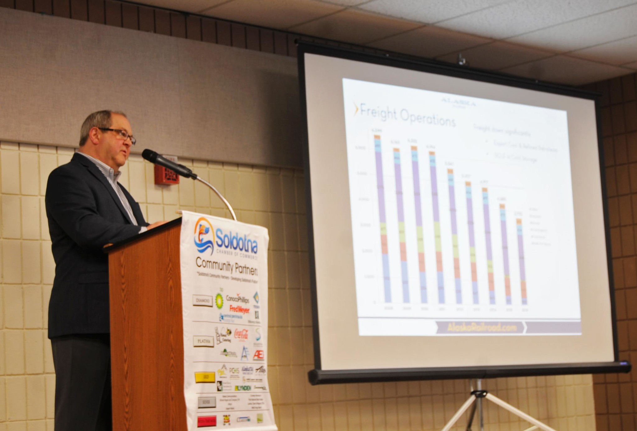 Dale Wade, the vice president of marketing and customer service for the Alaska Railroad Corporation, speaks to the joint Kenai and Soldotna chambers of commerce during a luncheon Tuesday, Feb. 14, 2017 at the Soldotna Regional Sports Complex in Soldotna, Alaska. Though the passenger service line of business is doing well, freight is not — on what Wade called “a fairly busy slide, but not a pretty slide,” bars depicted the steadily falling revenue in freight shipping, the railroad’s largest source of revenue. Most of the decline is due to decreased oil and gas activity, he said. (Elizabeth Earl/Peninsula Clarion)