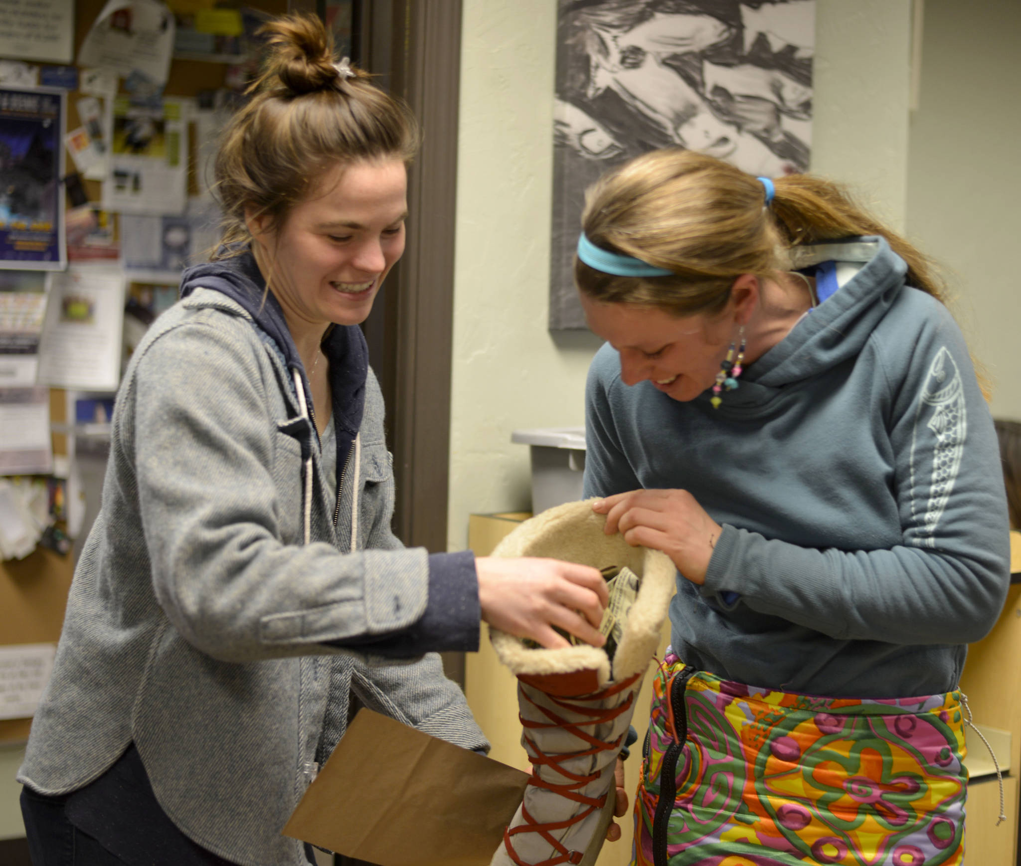 Kaitlin Vadla, left, of Cook Inletkeeper, returned Monica Zappa’s boot full of donations and tips for winning her fourth Iditarod at the Stand For Salmon send-off event on Tuesday, Feb. 28 2017, at Odie’s Deli in Soldotna. (Kat Sorensen/Peninsula Clarion)