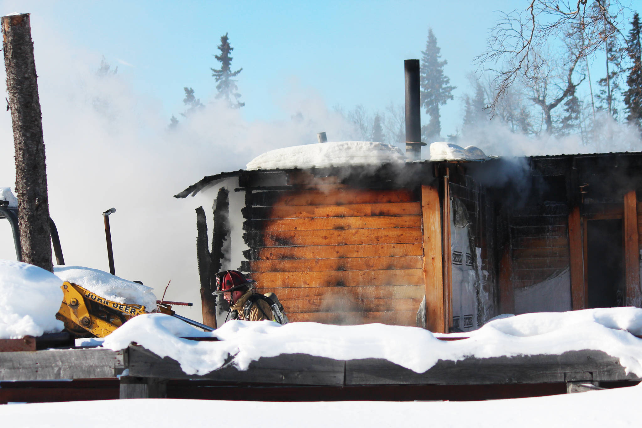 A firefighter walks past a burning house as members of the Nikiski Fire Department work to put out a fire Wednesday, March 1, 2017 on Bastien Drive in Nikiski, Alaska. No one was hurt in the fire, and the Kenai Fire Department provided mutual aid. (Megan Pacer/Peninsula Clarion)