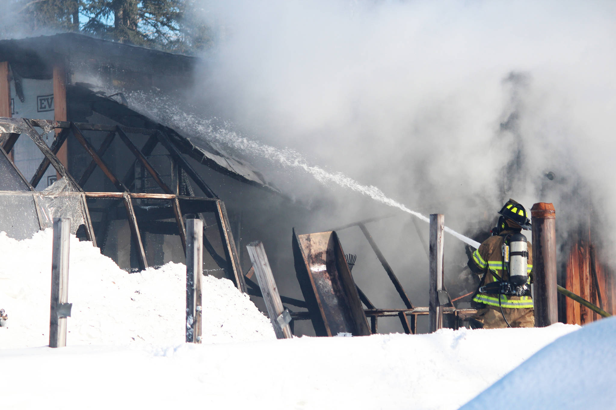 A firefighter aims water at a burning building Wednesday, March 1, 2017 at a residence on Bastien Drive in Nikiski, Alaska. The Nikiski and Kenai fire departments responded to a house fire Wednesday afternoon, in which no one was hurt. (Megan Pacer/Peninsula Clarion)