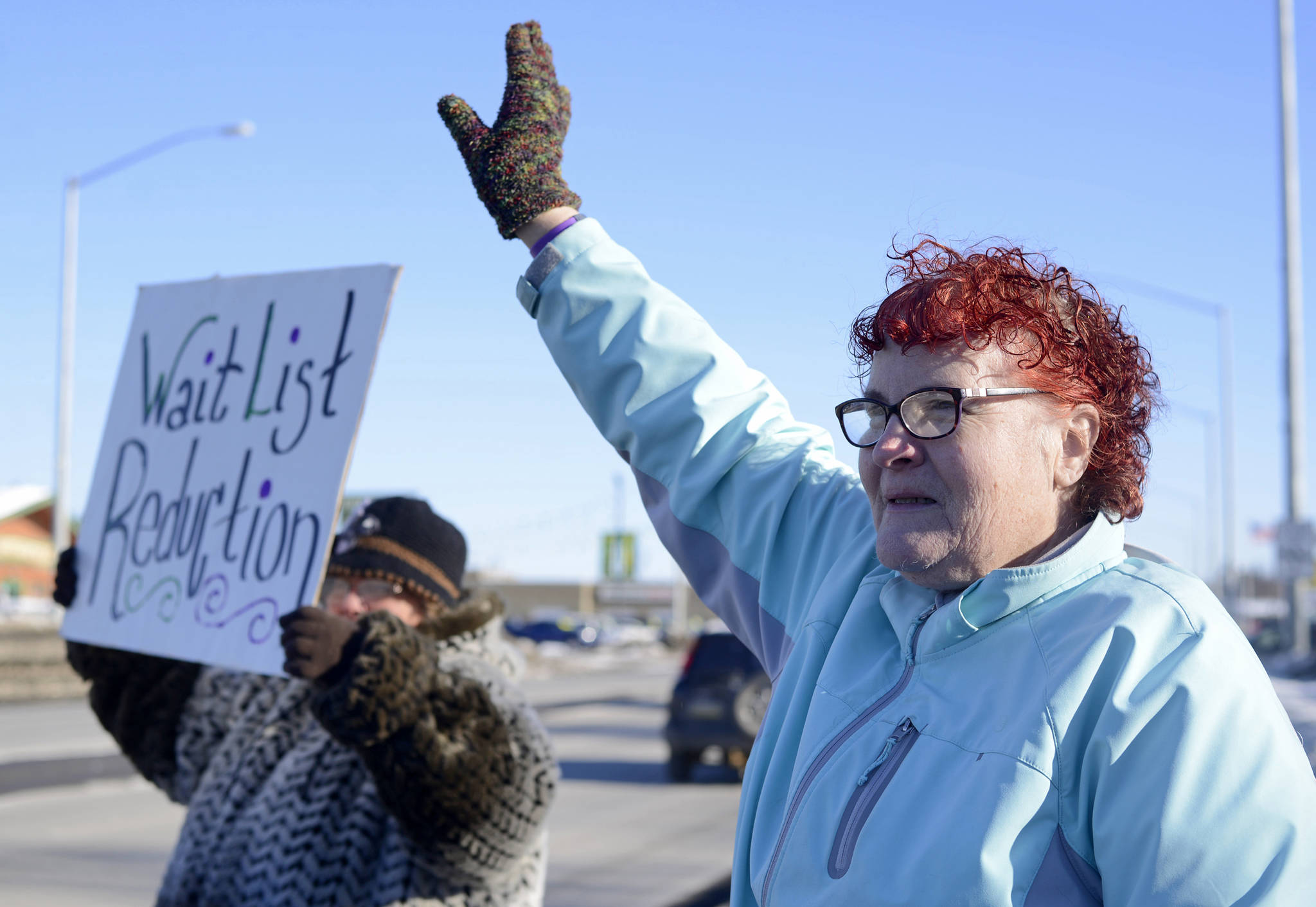 Teresa Reger (left, with sign) and Susie Stafford wave to passing cars at the annual demonstration in support of disability services by the Key Coalition advocacy group, held this year on Friday in Soldotna. Reger and Stafford are both parents of disabled adult children who receive services through the program the Key Campaign seeks to preserve. (Ben Boettger/Peninsula Clarion)