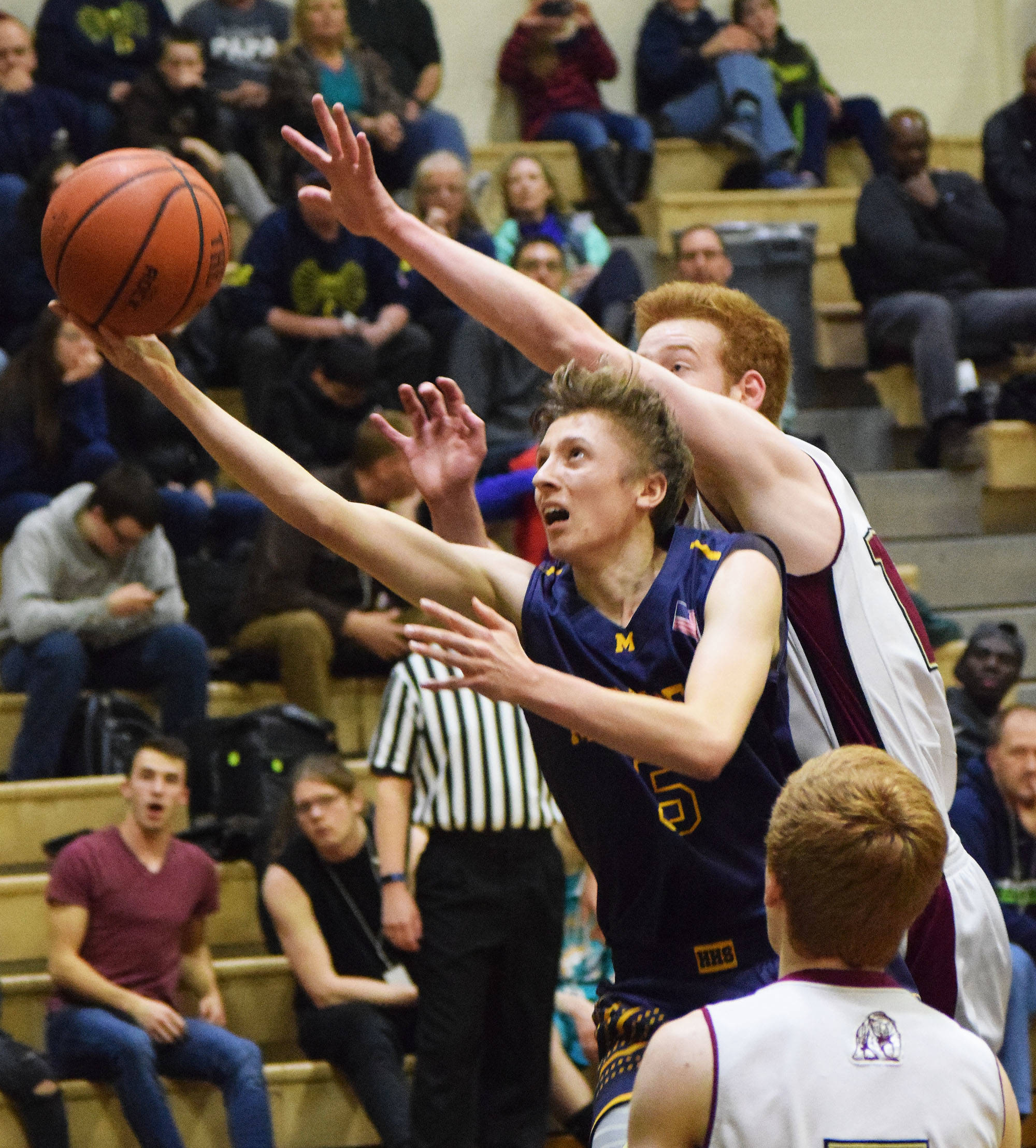 Homer’s Koby Etzwiler (5) reaches to score against Grace Christian’s Jimmy McGovern in a semifinal game Friday at the Southcentral Conference basketball tournament at Nikiski High School. (Photo by Joey Klecka/Peninsula Clarion)