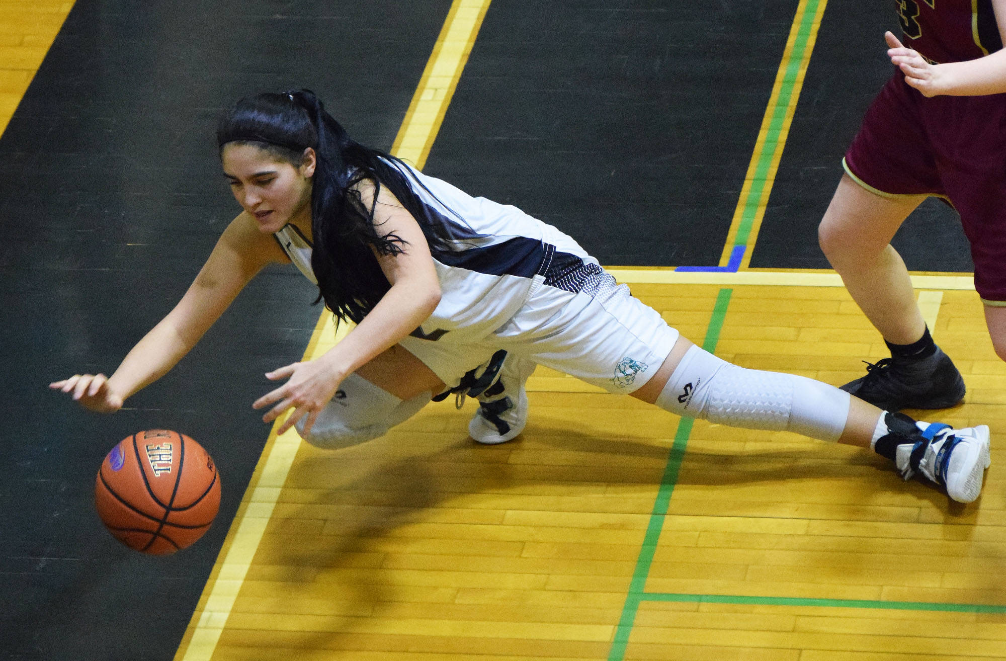 Nikiski’s Brianna Vollertsen dives for a loose ball against Grace Christian, Friday at the Southcentral Conference basketball tournament at Nikiski High School. (Photo by Joey Klecka/Peninsula Clarion)