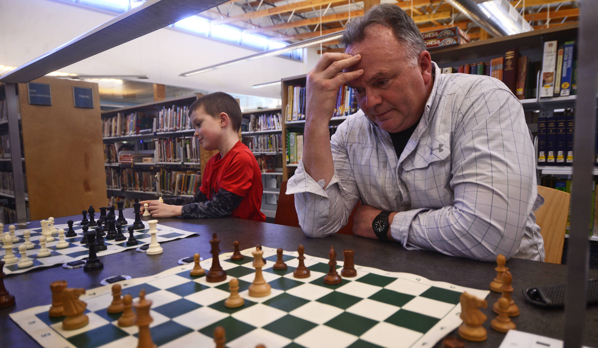 Hal Taylor (left) seeks an escape from check in a chess game against Andy Veh on Tuesday, March 21, 2017 in the Kenai Community Library. Taylor helped organize a chess club that plays in the Kenai Library every Tuesday at 4 p.m.