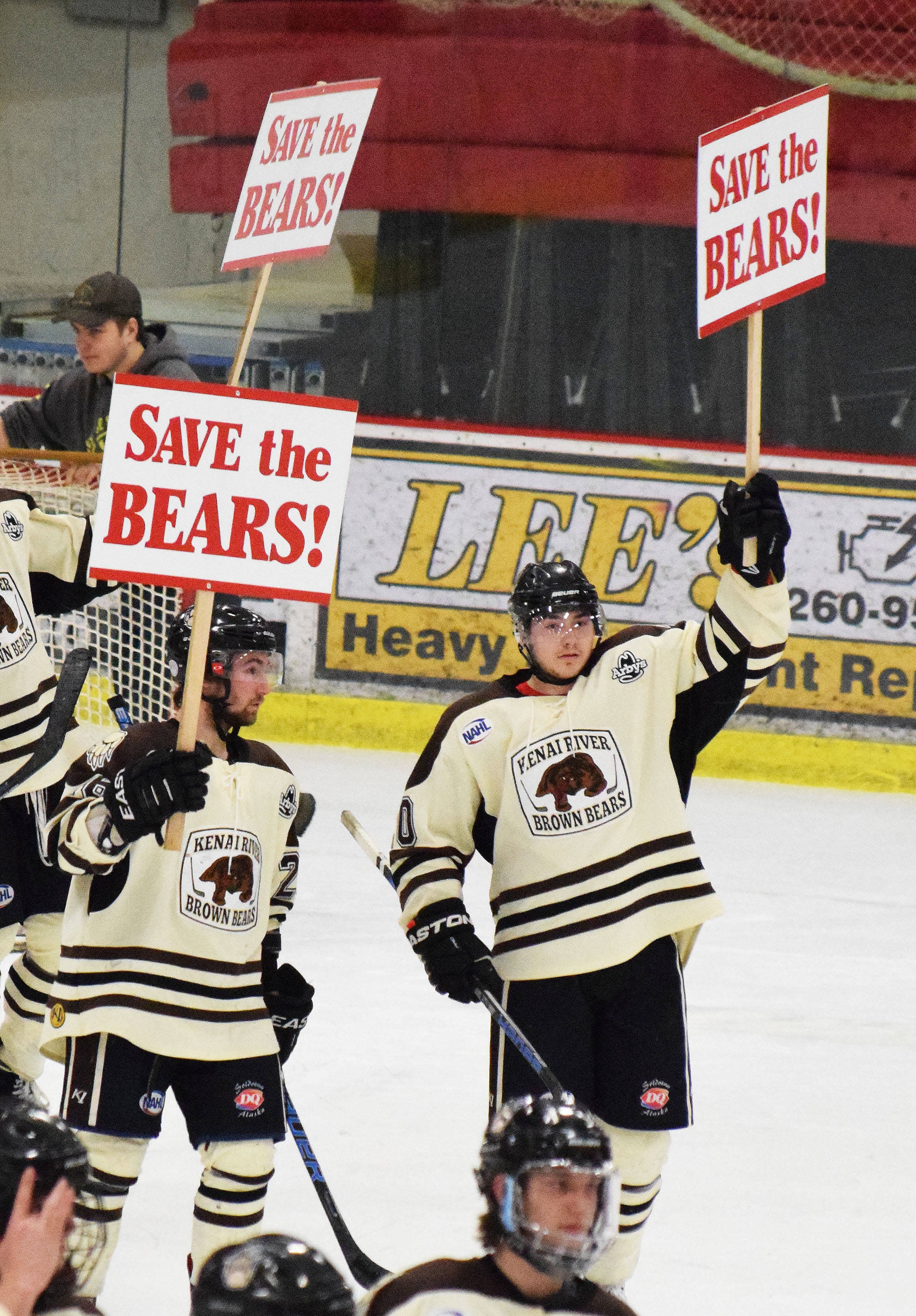 Kenai River’s Jonathan Marzec (left) and Jake Friedman hold up signs Saturday night advocating for the return of the Brown Bears organization next season at the Soldotna Regional Sports Complex.