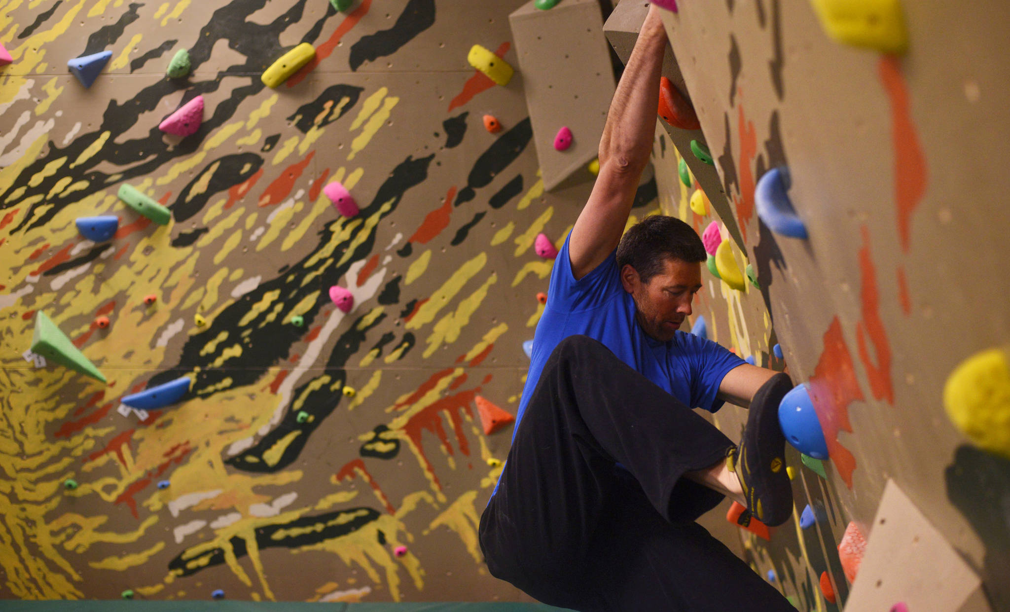 Nathan Beck works his way across a bouldering wall he co-designed, with Ed Schmitt, at the River City Wellness Center gym on Wednesday, March 29, 2017 in Soldotna, Alaska. The new wall, featuring stylized landscape art by Kaitlin Vadla, will have a grand opening on Saturday, April 8 from 4 p.m to 6 p.m. Admission will be $20.