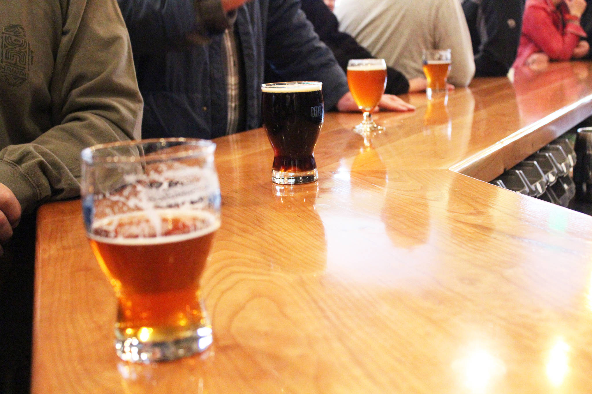 Patrons stand at the bar with their drink Friday, March 31, 2017 at Kenai River Brewing Company in Soldotna, Alaska. Soldotna is one of several communities in the state with establishments that opened under public convenience licenses, which would be transitioned to restaurant or eating place license types under SB 76, a rewrite of Alaska’s alcohol statutes. (Megan Pacer/Peninsula Clarion)