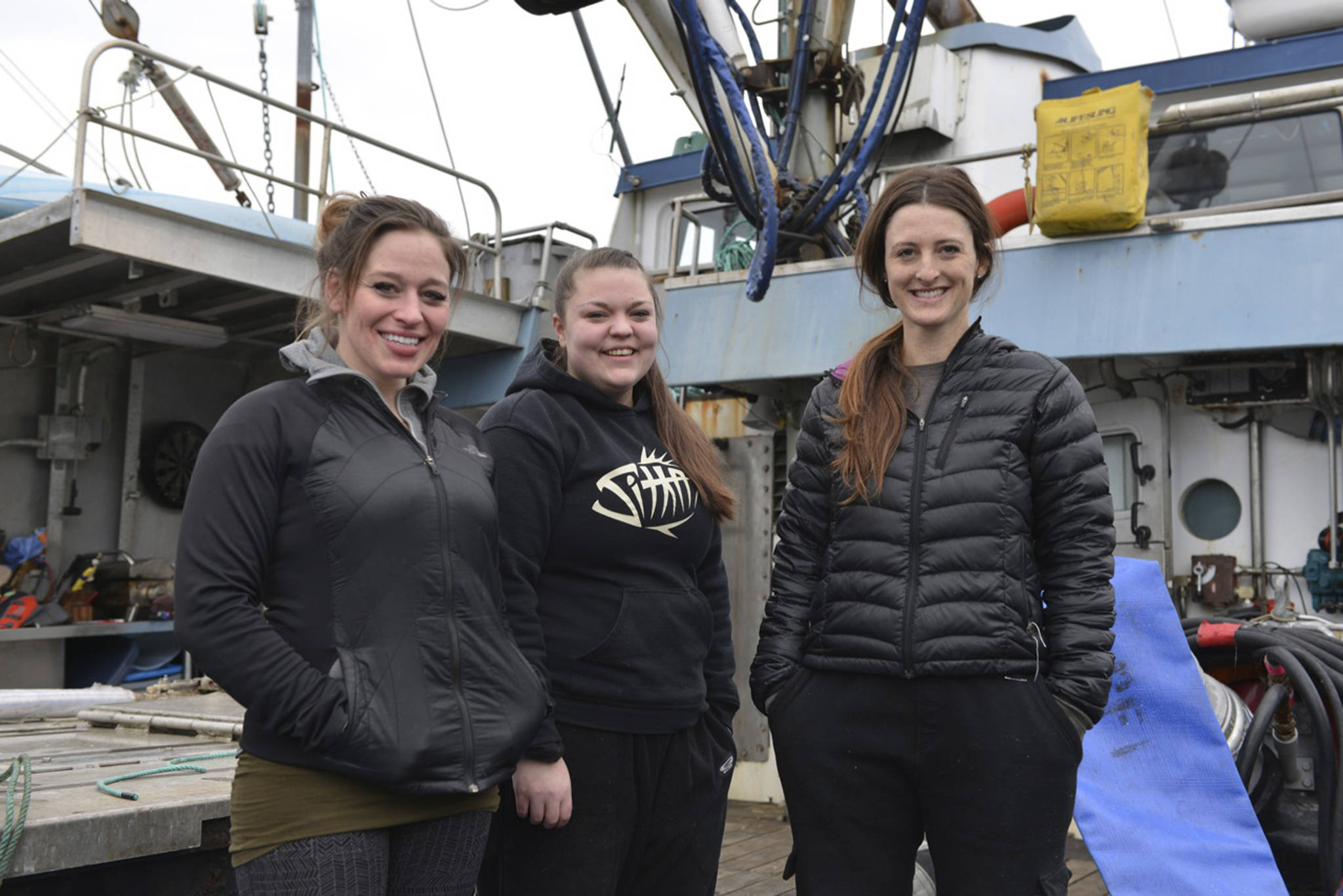 In this March 17, 2017 photo, Brannon Finney, from left, Kelsey Kubik and Bettina Nichols stand on the deck of the fishing tender Kamilar in the morning at Eliason Harbor in Sitka, Alaska. On a door of the F/V Kamilar is a sticker with pink script: Girls fish too. Vessel owner Finney is captaining the tender for the Sitka sac roe herring fishery with her all-female crew, something that&