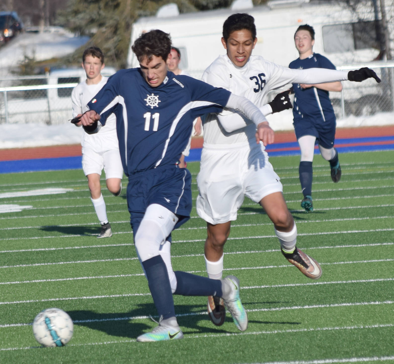 Homer’s Charlie Menke shields Soldotna’s Alex Montague from the ball Tuesday, April 11, 2017, at Soldotna High School. (Photo by Jeff Helminiak/Peninsula Clarion)