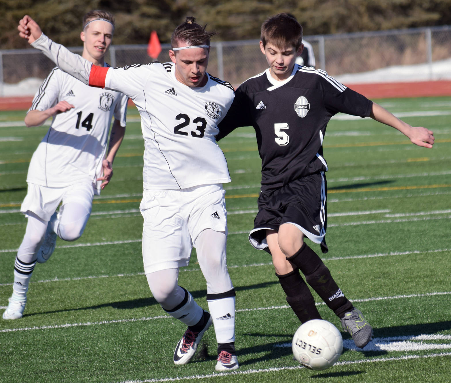 Kenai Central’s Zack Tuttle and Nikiski’s Mason Payne battle for the ball Wednesday, April 12, 2017, at Kenai Central High School. (Photo by Jeff Helminiak/Peninsula Clarion)