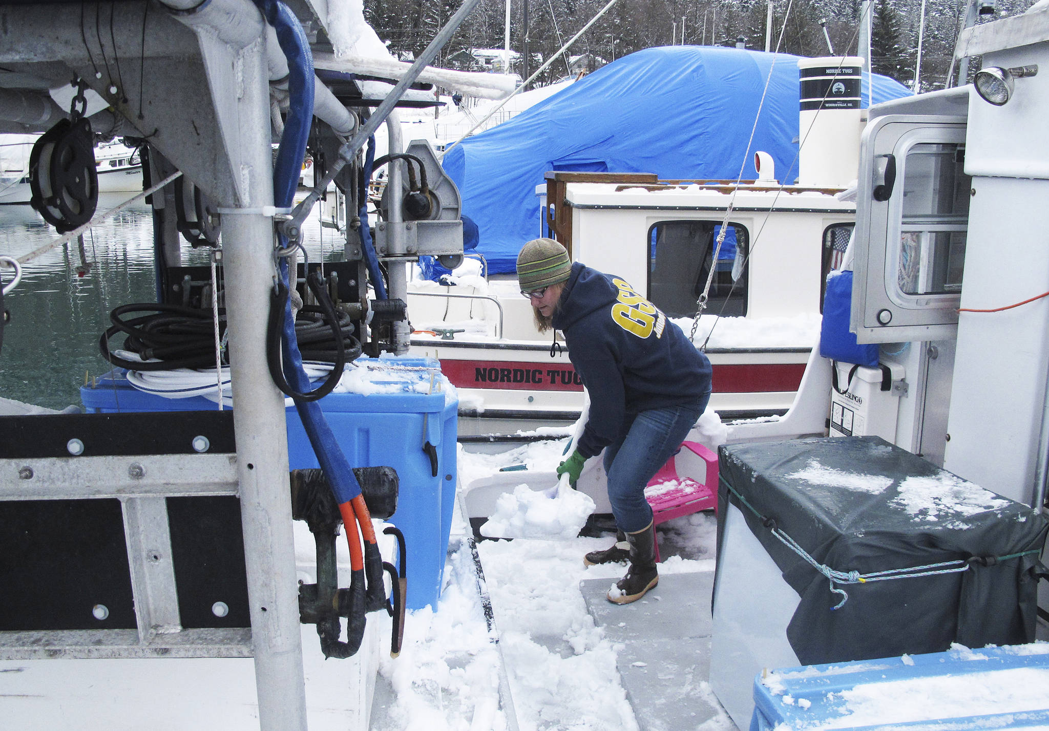 In this March 15, 2017 photo, Bonnin Jarvill, who fishes with her husband and young daughter, shovels snow from the boat that doubles as home and workplace in Juneau, Alaska. Jarvill says health care costs are a constant concern for her. (AP Photo/Becky Bohrer)