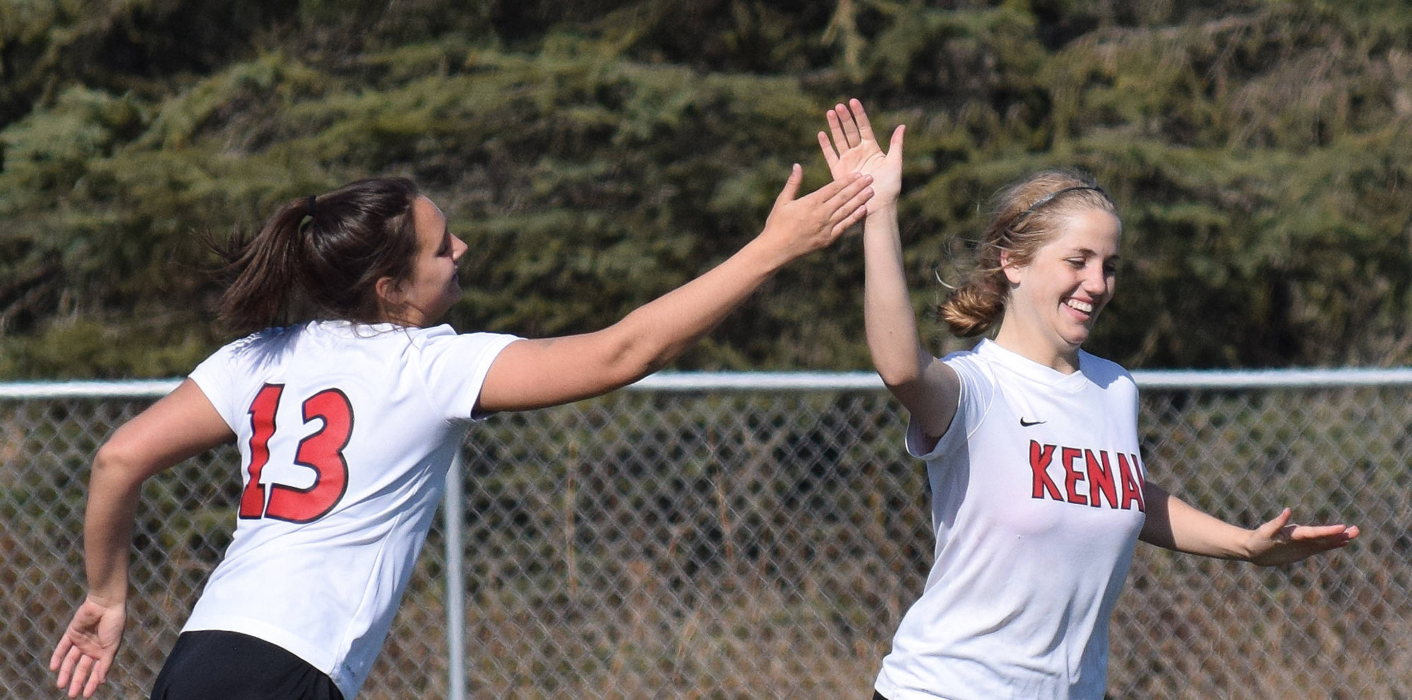 Kenai Central’s Faith Ivy (left) gives teammate Emily Halstead a high five after Halstead scored in the second half against Nikiski Friday afternoon at Ed Hollier Field in Kenai. (Photo by Joey Klecka/Peninsula Clarion)