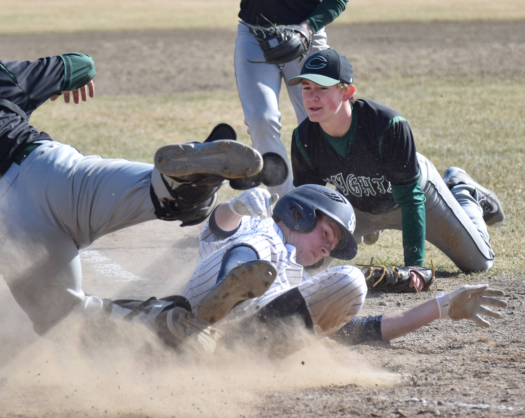 Soldotna’s Jeremy Kupferschmid slides safely to home plate to tie the game while Colony pitcher Trace Severson looks on, Tuesday afternoon at the Soldotna baseball fields. (Photo by Joey Klecka/Peninsula Clarion)