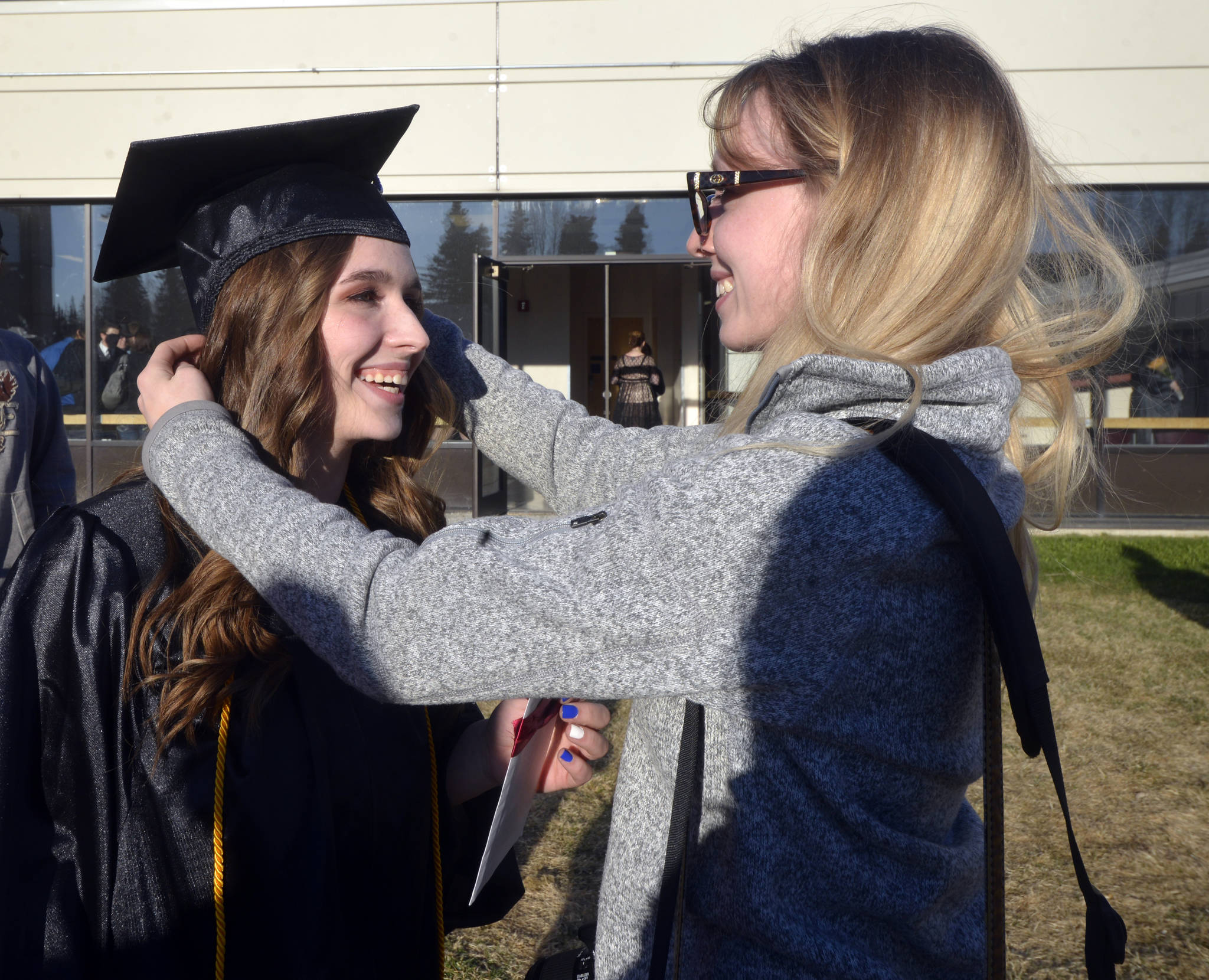 LeAnna Hobby, right, adjusts Allison Bushnell’s cap before taking photos following the Kenai Peninsula College graduation Thursday, May 11, 2017 at Ren&