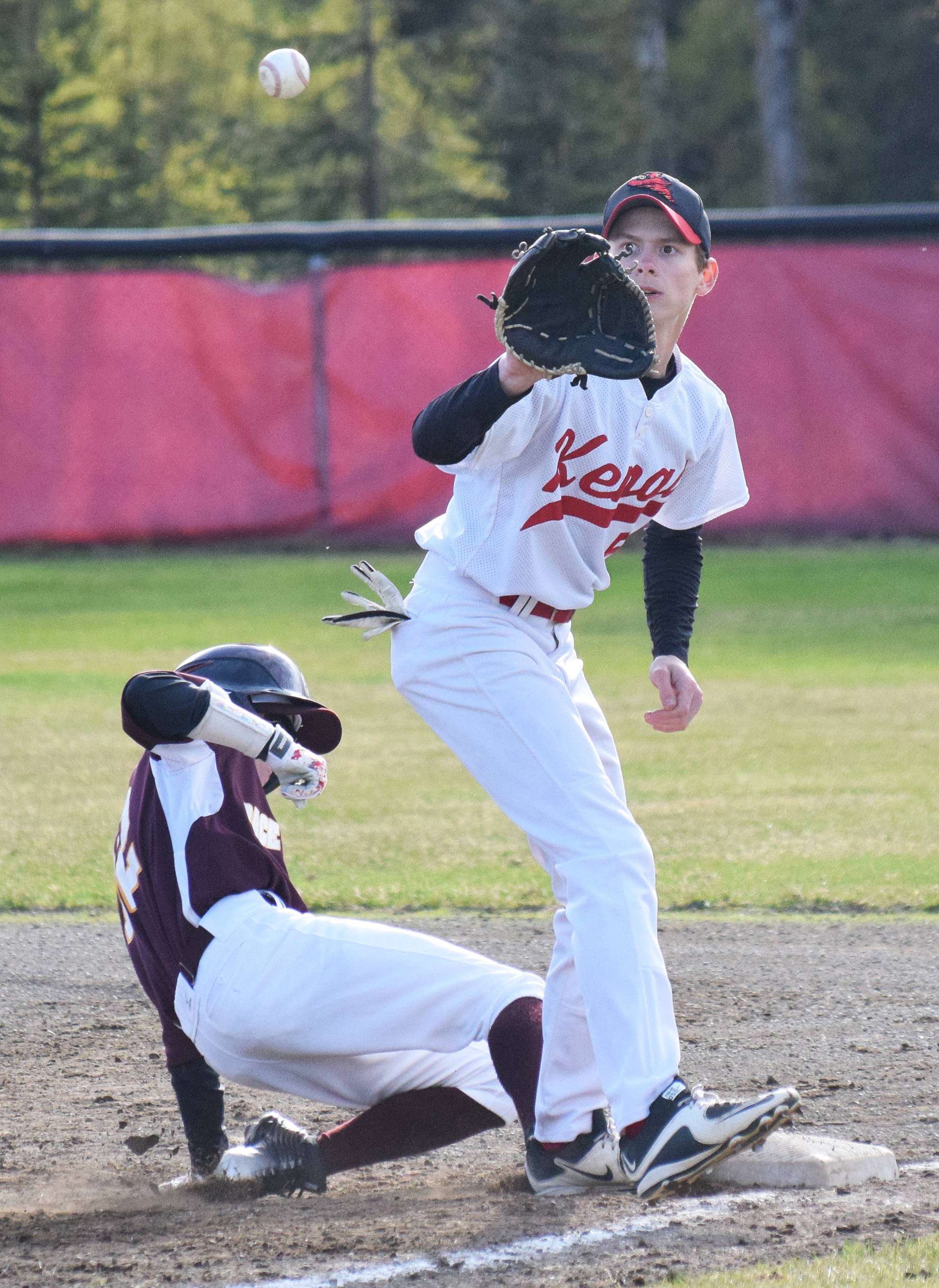 Kenai Central first baseman Levi Mese attempts to put out Grace Christian’s Parker Hovila, Friday evening at the Kenai Little League Fields. (Photo by Joey Klecka/Peninsula Clarion)