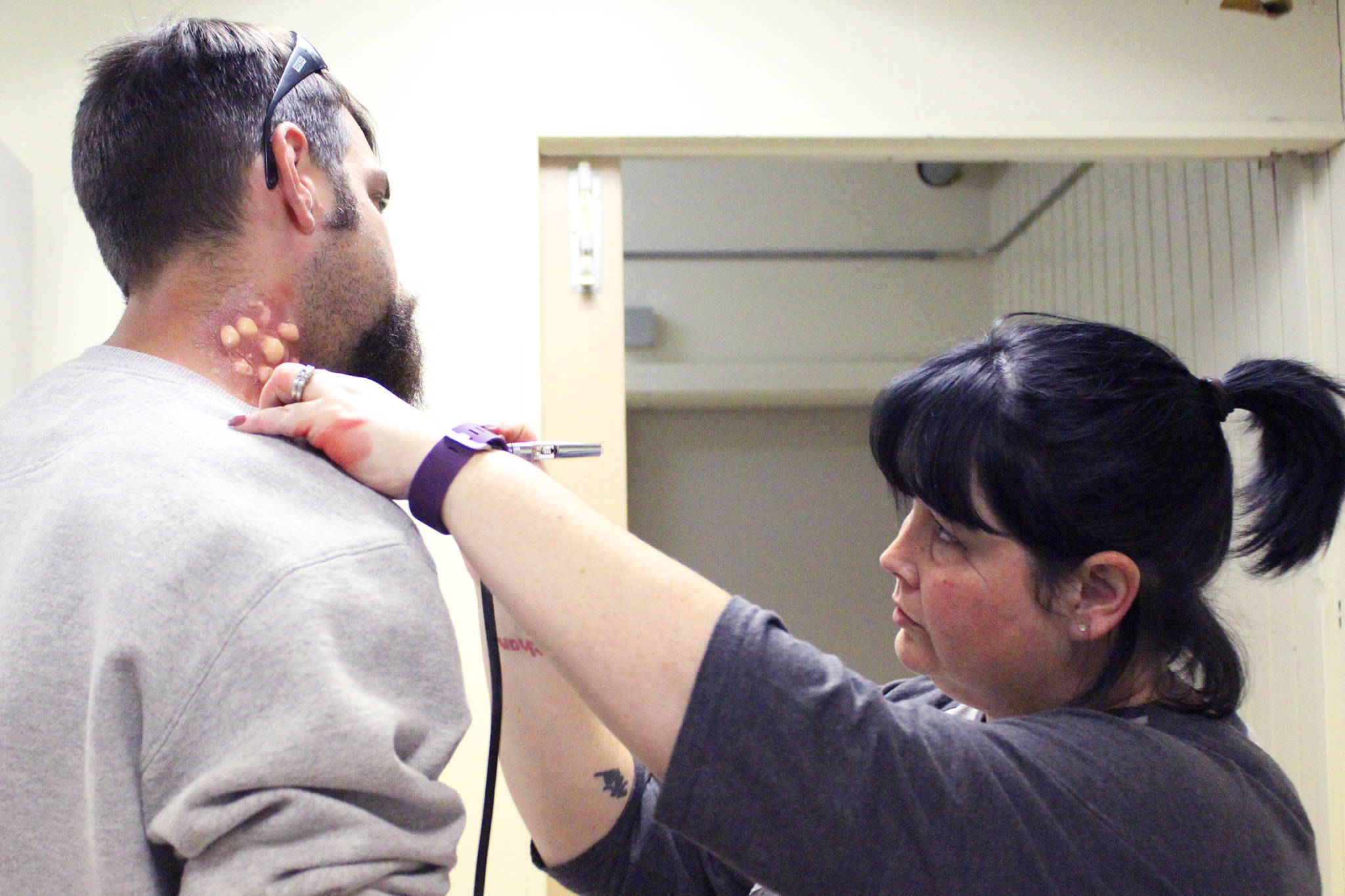 Lead Affects Artist Heather Westrum applies makeup to Trauma Amputee Actor Nathan Lieber to make it look like he suffers from chemical burns just before a training exercise consisting of multiple emergency scenarios, inlcuding a meth lab explosion, Saturday, May 20, 2017 at the North Peninsula Recreation Center in Nikiski, Alaska. JTM Training Group in Las Vegas, where Lieber and Westrum work, has traveled to Alaska for the last six years to host courses that help train members of law enforcement and emergency medical services to better coordinate when responding to calls that turn violent. (Megan Pacer/Peninsula Clarion)
