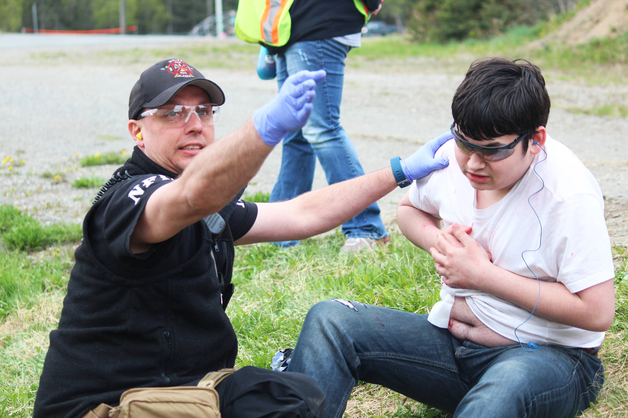 A member of the Nikiski Fire Department directs his fellow teammates while tending to the fake injuries of 14-year-old Petie Deveer during a simulated meth lab explosion Saturday, May 20, 2017 at the North Peninsula Recreation Center in Nikiski, Alaska. Several members of Kenai Peninsula law enforcement agencies and emergency medical service organizations have been taking a multi-day course focused on working together on violent calls from Las Vegas-based JTM Training Group, which culminated in Saturday’s emergency drills. (Megan Pacer/Peninsula Clarion)